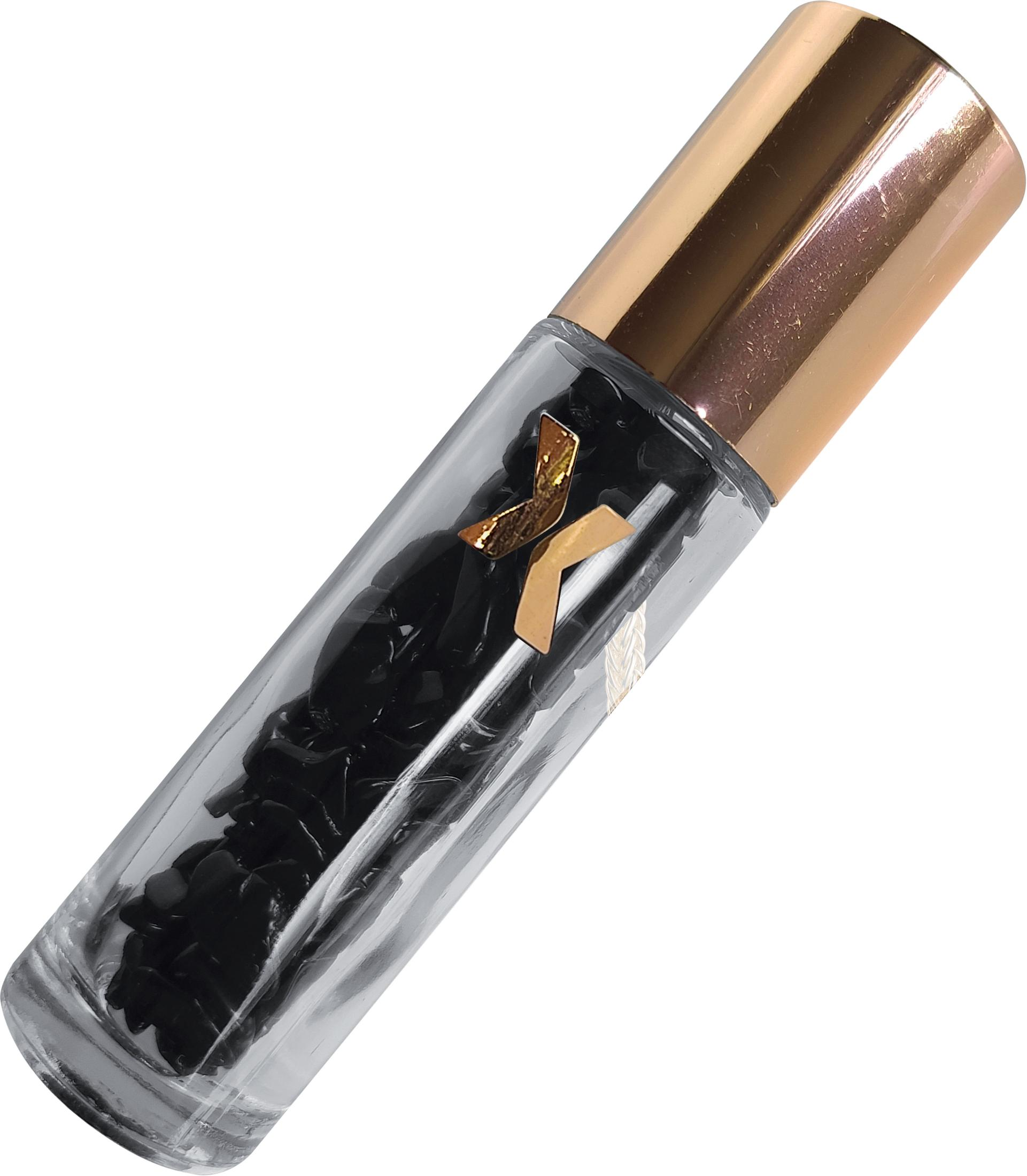 Eine klare Glasflasche mit schwarzen Steinen, goldener Kappe und Logo. Abgewinkelt auf weißem Hintergrund.