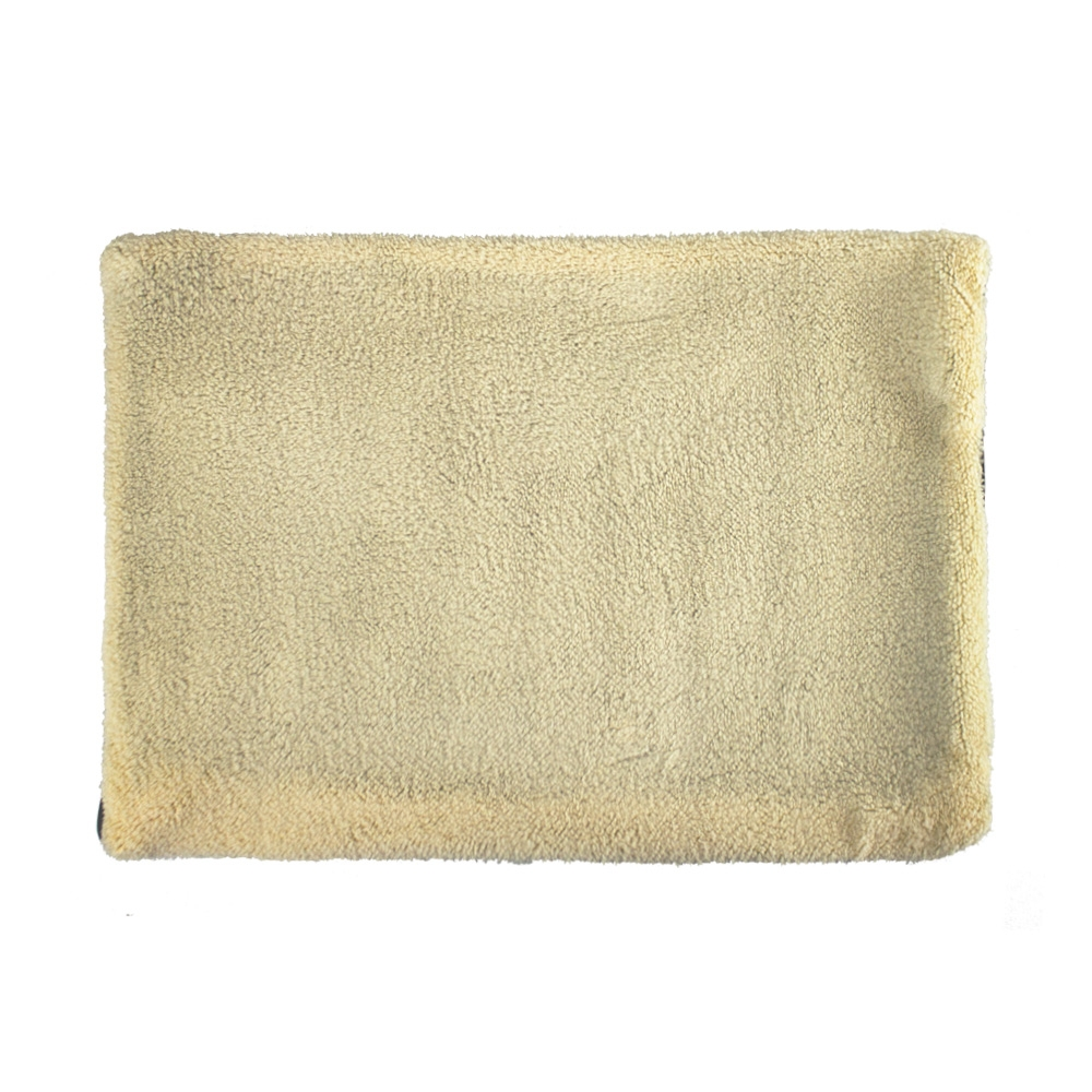Una tela rectangular, color crema, suave y texturizada, posiblemente una cama para mascotas o una toalla, sobre un fondo blanco.