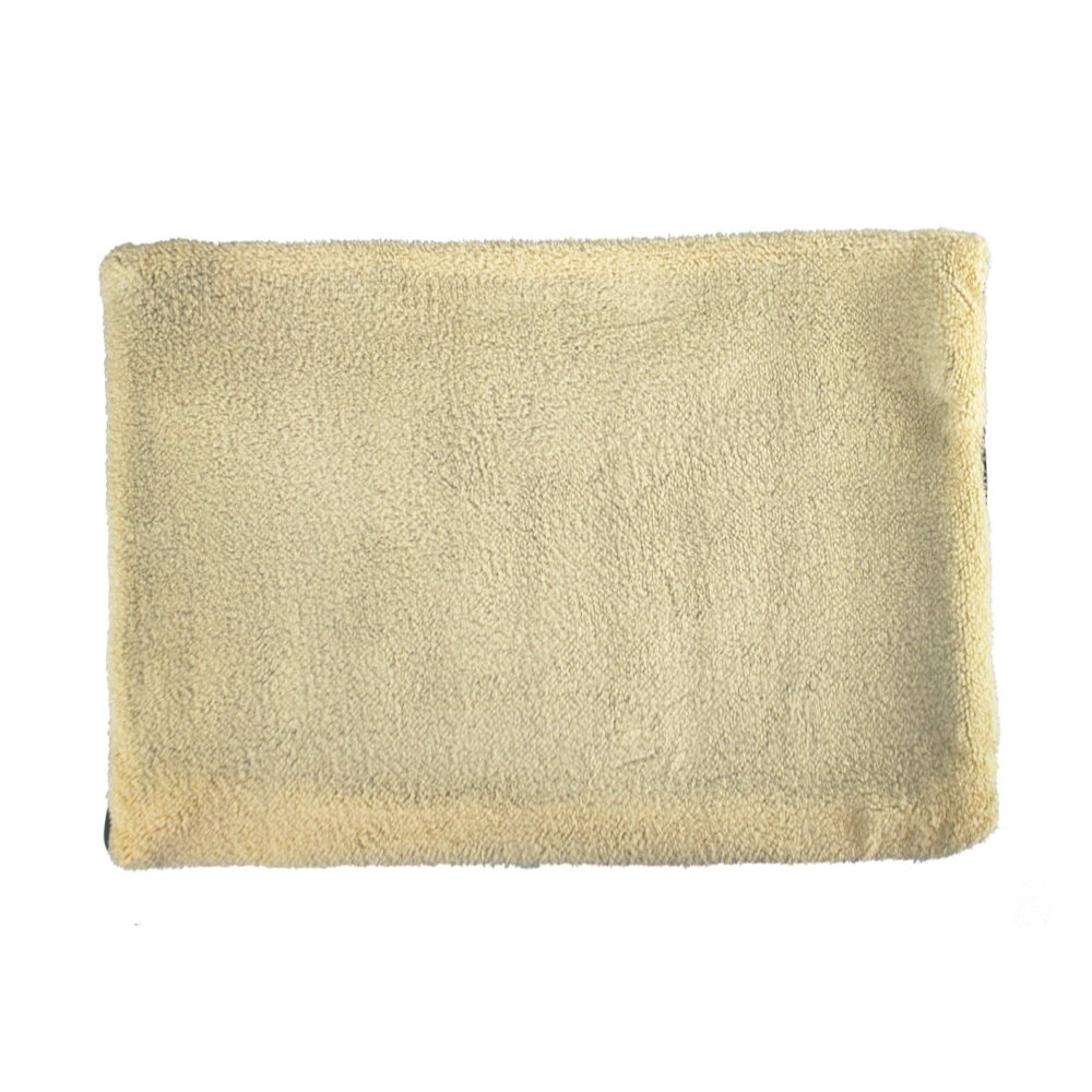 Una toalla rectangular, color crema y esponjosa sobre un fondo blanco. La toalla tiene una superficie suave y texturizada.
