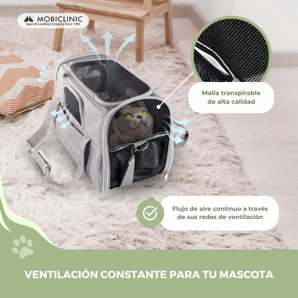 Un gato gris dentro de un transportín gris. Está sobre una alfombra. El texto indica ventilación constante.