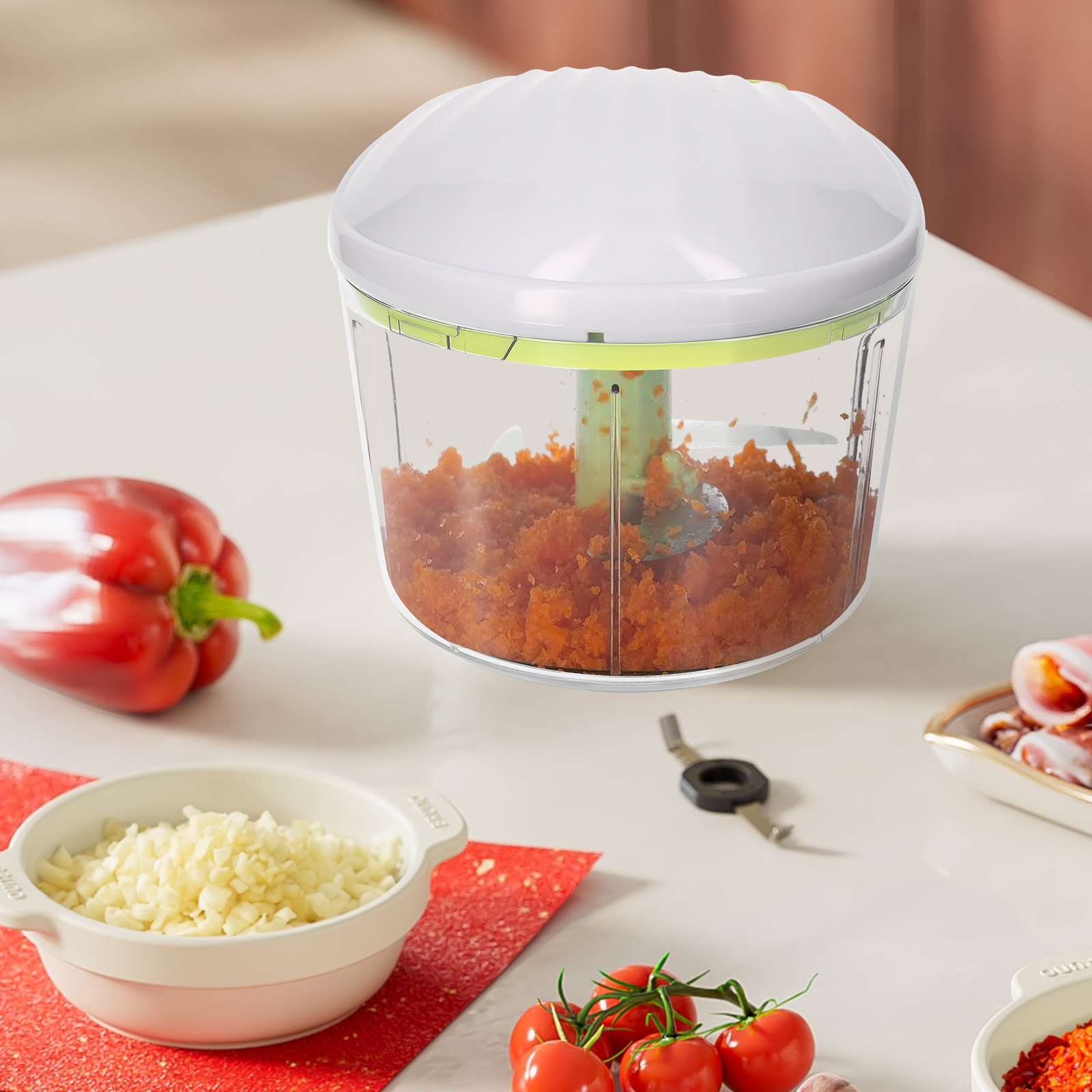 Un tritatutto con carote tritate all'interno. Peperone rosso, pomodori e altri ingredienti sul tavolo.