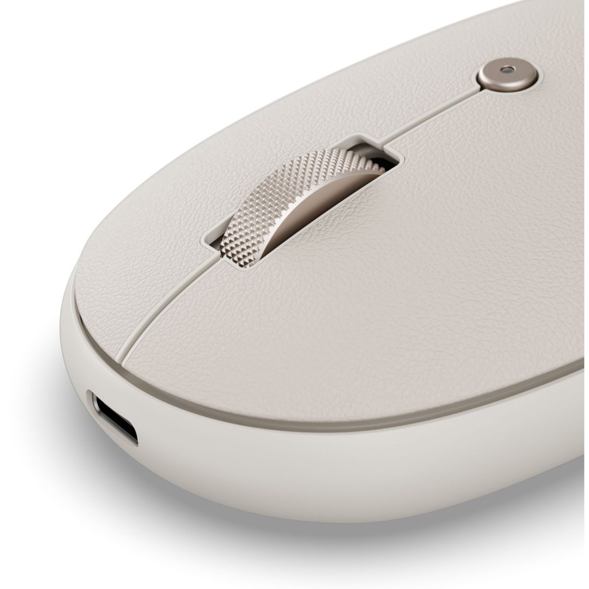 Primo piano di un mouse wireless bianco. Ha una parte superiore strutturata, una rotella di scorrimento e una porta di ricarica. Lo sfondo è bianco.