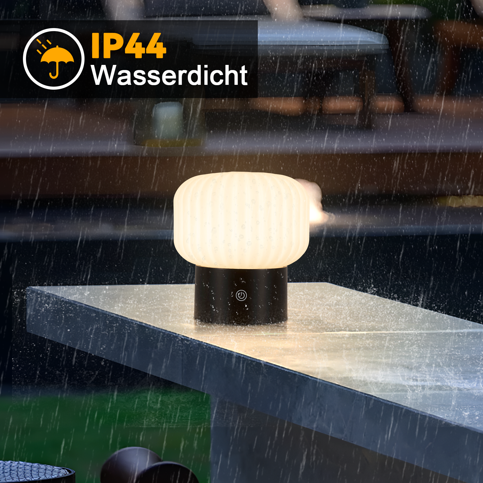 Świecąca lampa na stole, pada deszcz. Lampa jest czarno-biała, z klasą szczelności IP44.