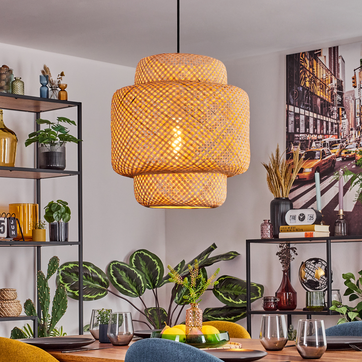 Ein Esszimmer mit einer großen gewebten Lampe, einem Tisch mit Gläsern und Tellern sowie Pflanzen. Ein Stadtbildgemälde hängt an der Wand.