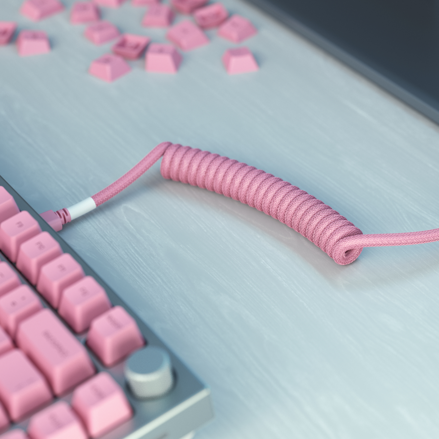 Açık renkli ahşap bir yüzey üzerinde pembe spiralli bir klavye kablosu ve pembe tuşlara sahip bir klavye. Bazı tuş başlıkları dağılmış.