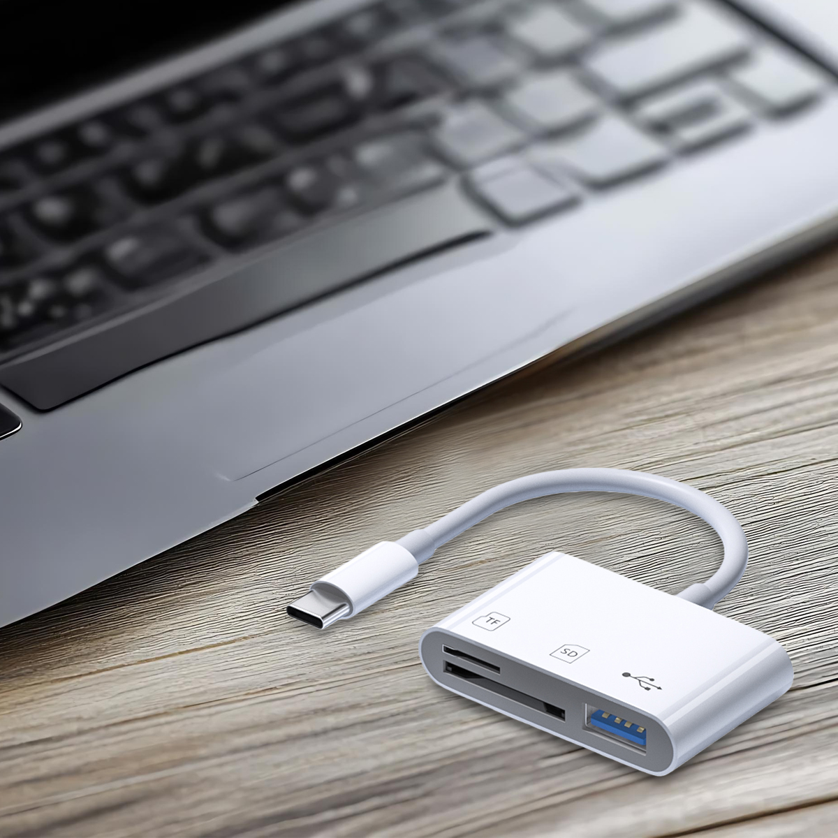 Ein weißer USB-C-Kartenleser neben einem Laptop auf einer Holzoberfläche. Der Leser hat SD- und TF-Steckplätze.