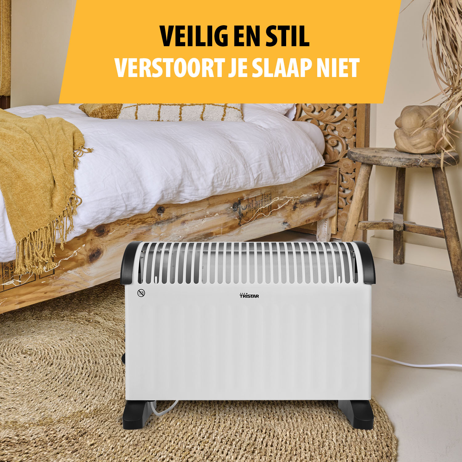 Een witte Tristar-kachel staat op een vloerkleed in een slaapkamer. Een bed en een houten krukje op de achtergrond. Tekst: VEILIG EN STIL.