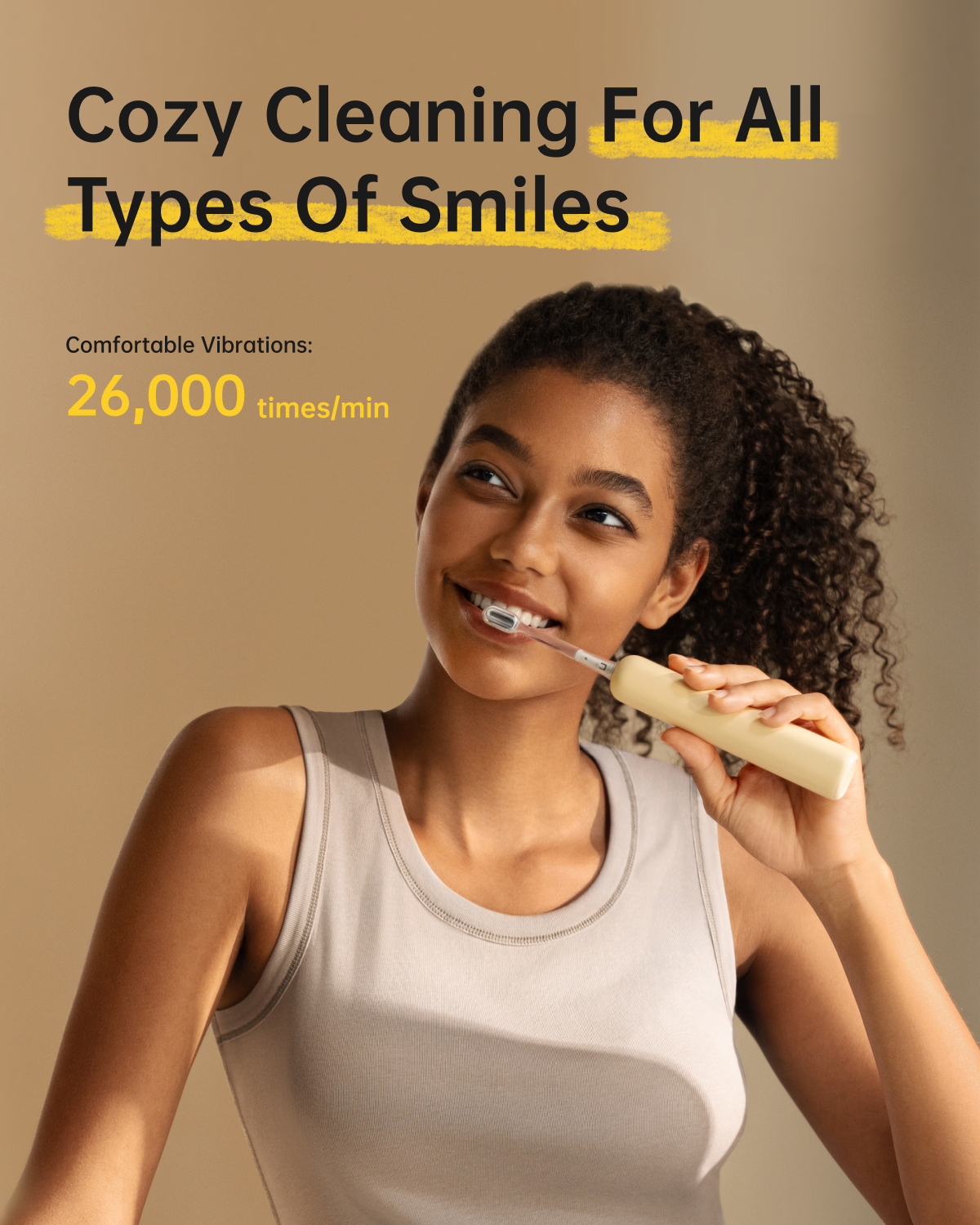 Eine Frau putzt sich mit einer elektrischen Zahnbürste die Zähne und lächelt. Text: Cozy Cleaning For All Types Of Smiles. 26.000 Mal/Min.