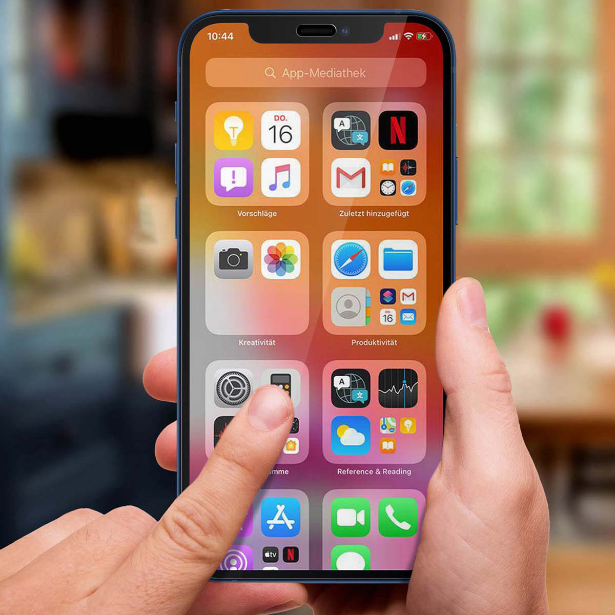 Hand houdt blauwe iPhone vast met app-iconen. Vinger raakt het scherm aan. Achtergrond wazig, houten textuur.