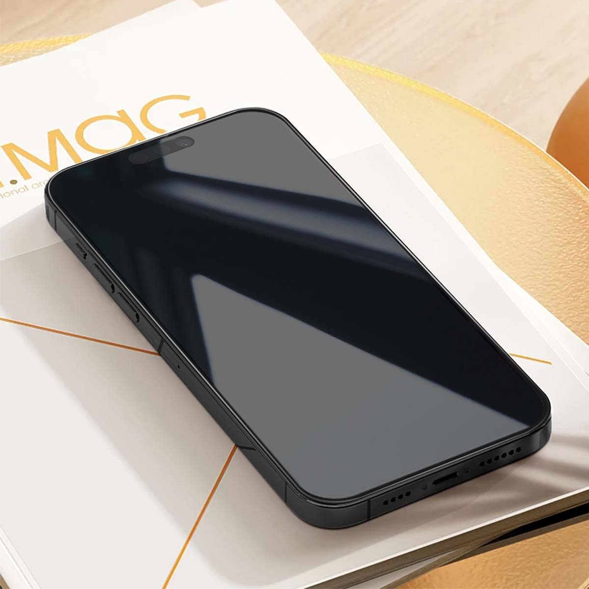 Uno smartphone nero è appoggiato su una rivista bianca con la parola 'MAG'. Lo schermo riflette l'ambiente circostante.