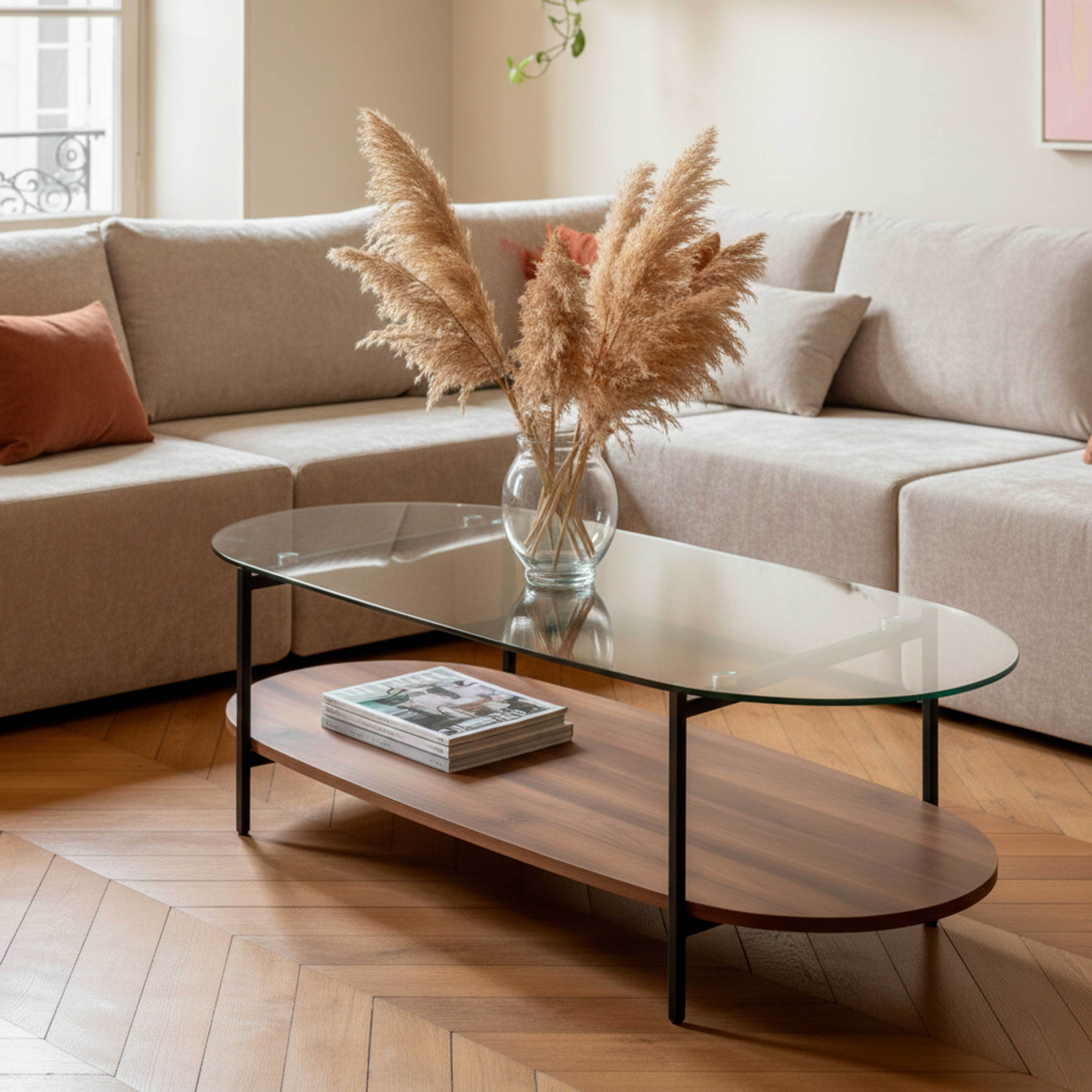 Ein modernes Wohnzimmer mit einem Couchtisch mit Glasplatte. Eine Vase mit Trockenblumen steht darauf. Im Hintergrund befindet sich ein Sofa.