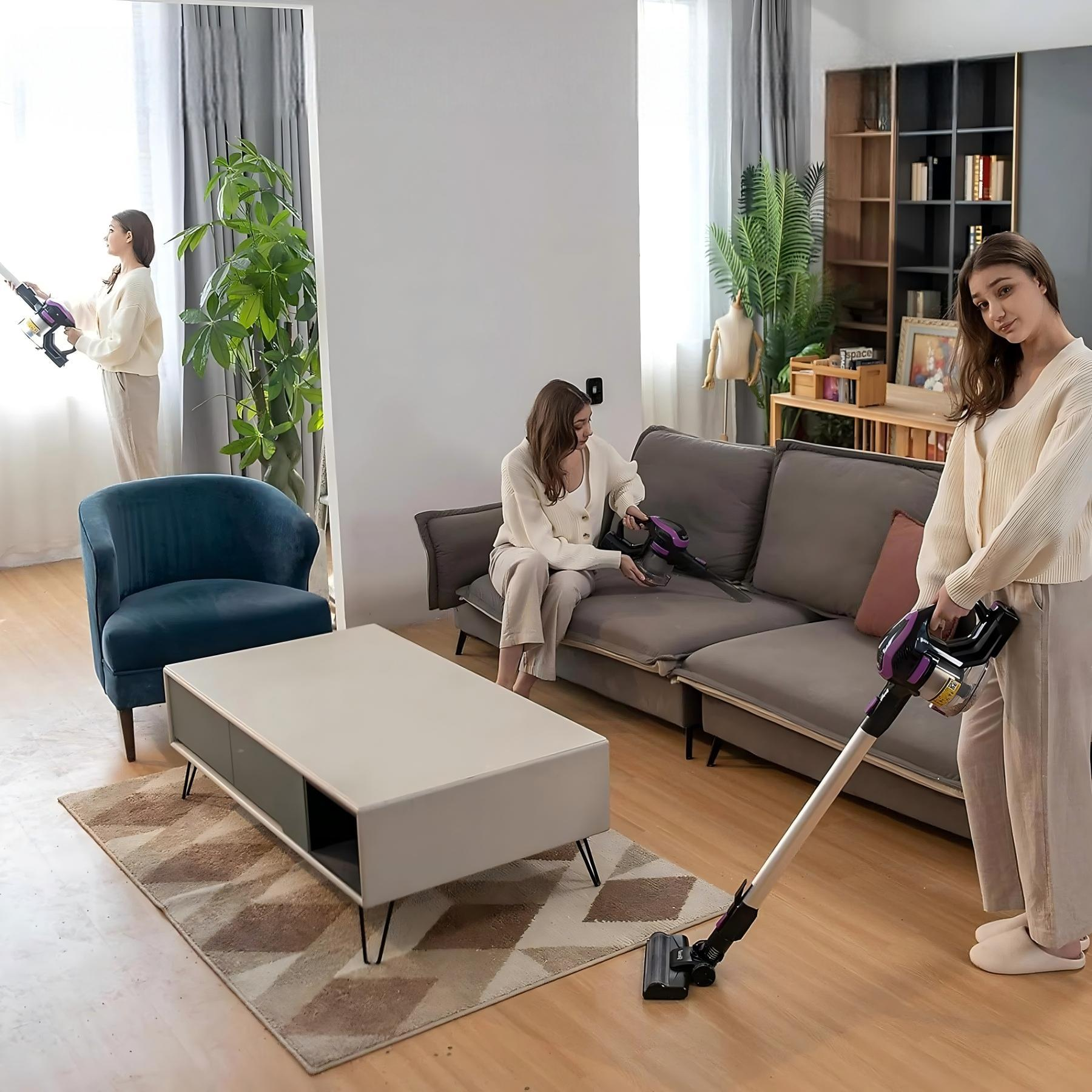 Trzy kobiety odkurzają salon. Jedna przy oknie, jedna na sofie, a jedna stojąca z odkurzaczem.