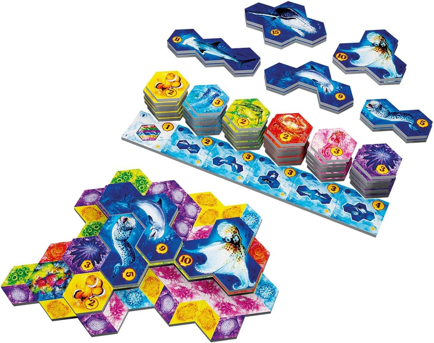 Brettspiel mit Meeresbewohnern. Auf sechseckigen und anderen Spielsteinen sind Delfine, Oktopusse und andere Meereslebewesen abgebildet.