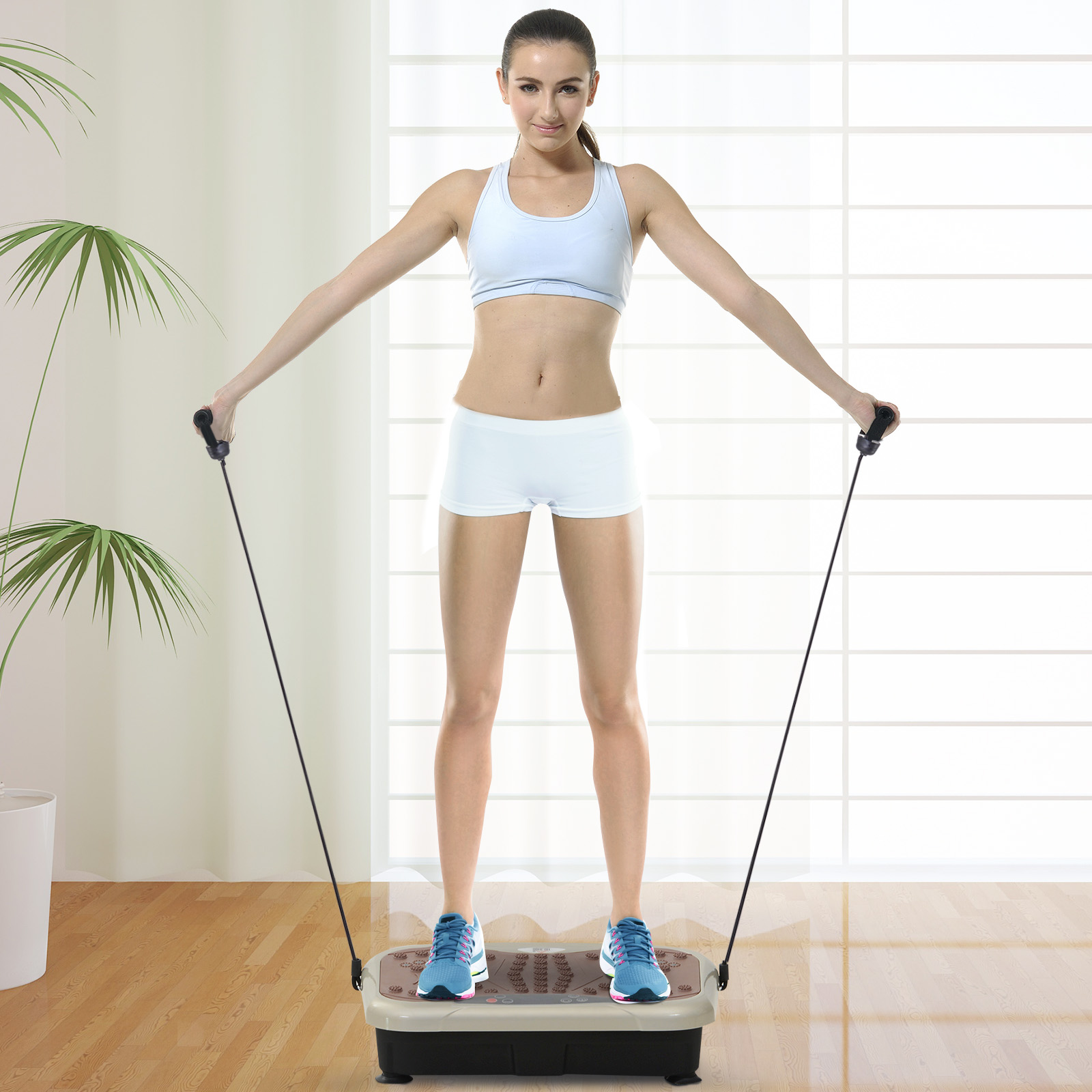 Eine Frau in Sportkleidung steht auf einer Vibrationsplatte und hält Seile.