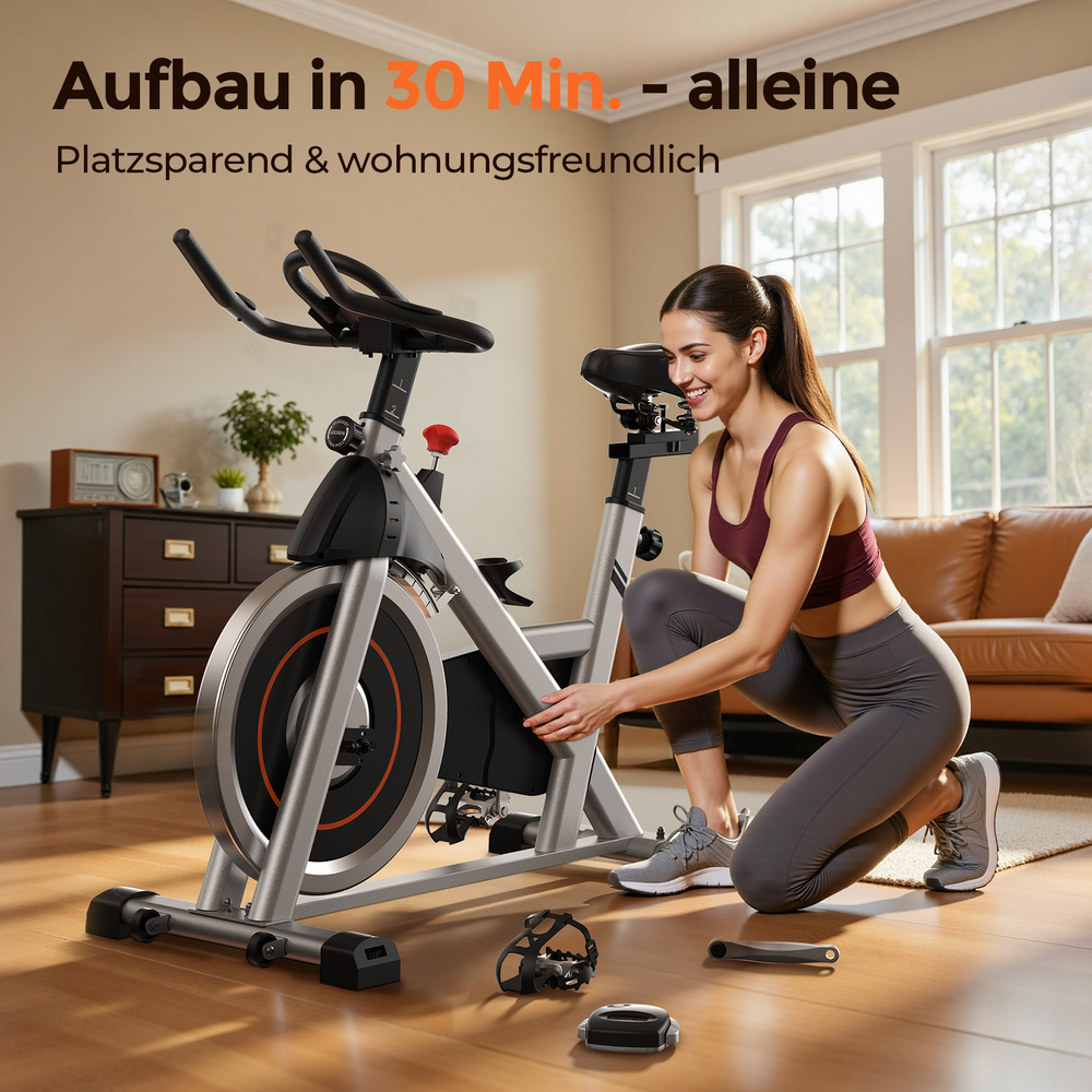 Eine Frau kniet neben einem silbernen Heimtrainer und lächelt. Teile liegen auf dem Boden.