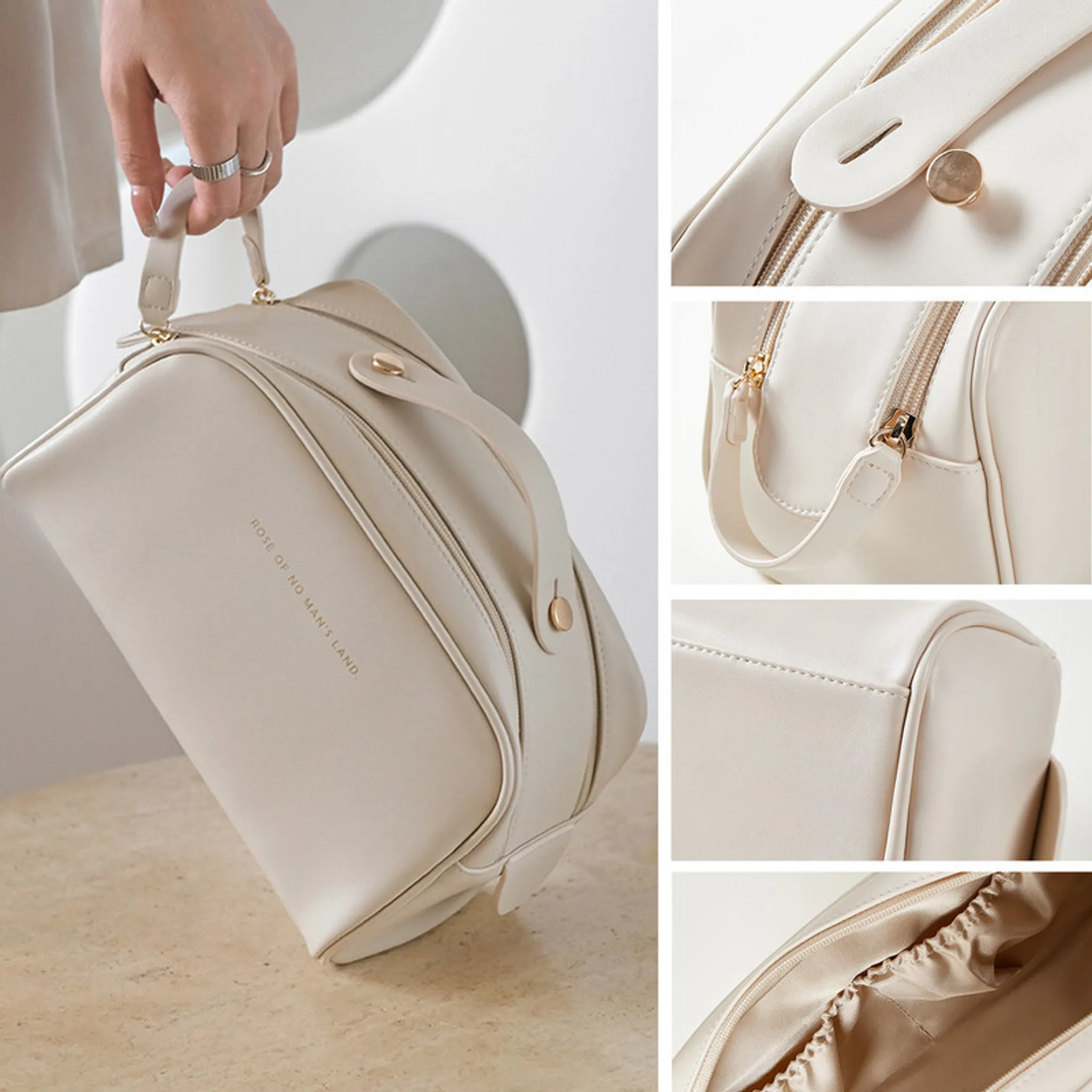 Eine Person hält eine cremefarbene Kosmetiktasche mit goldenen Reißverschlüssen und einem Griff.