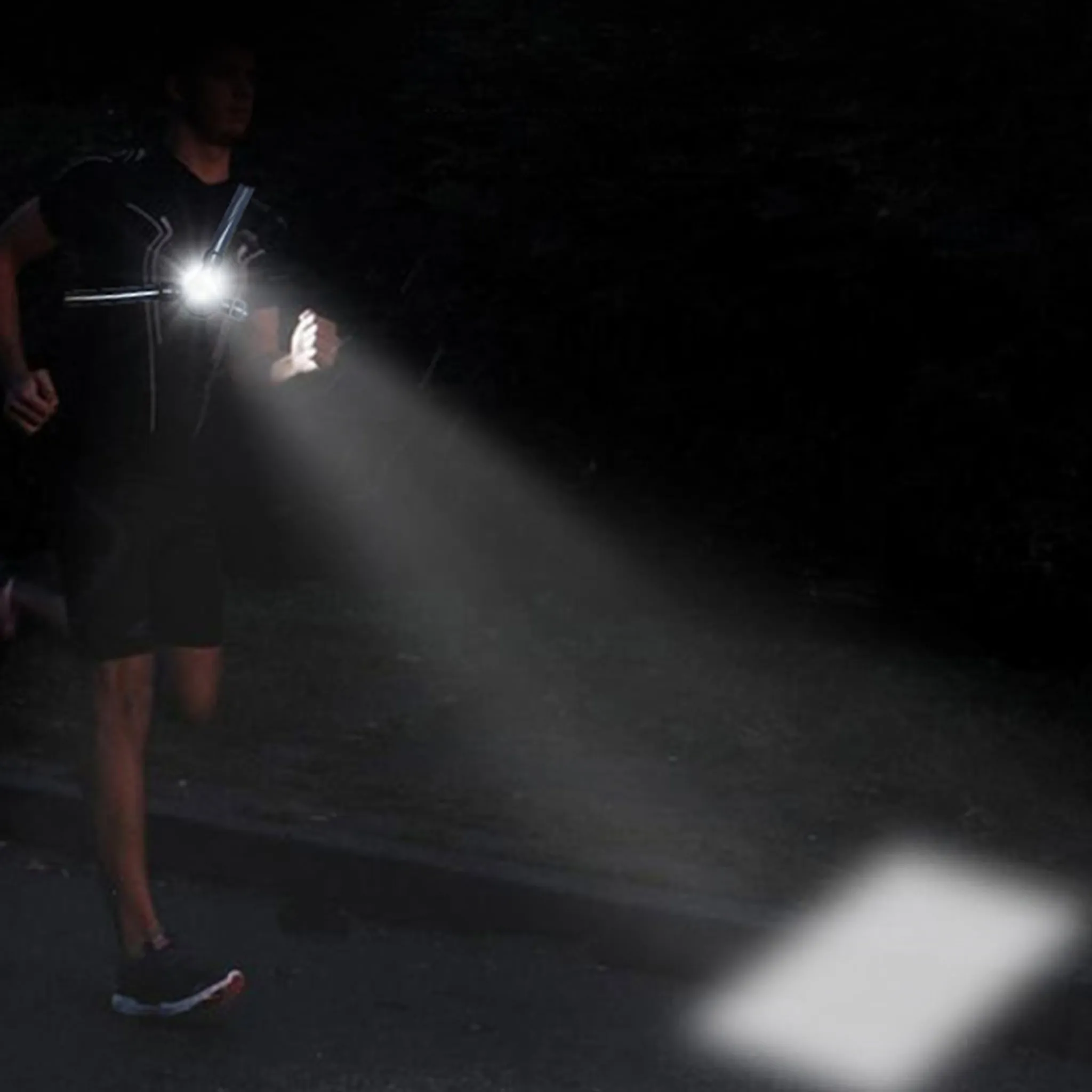 Ein Mann rennt nachts mit einer Stirnlampe auf einem dunklen Weg.