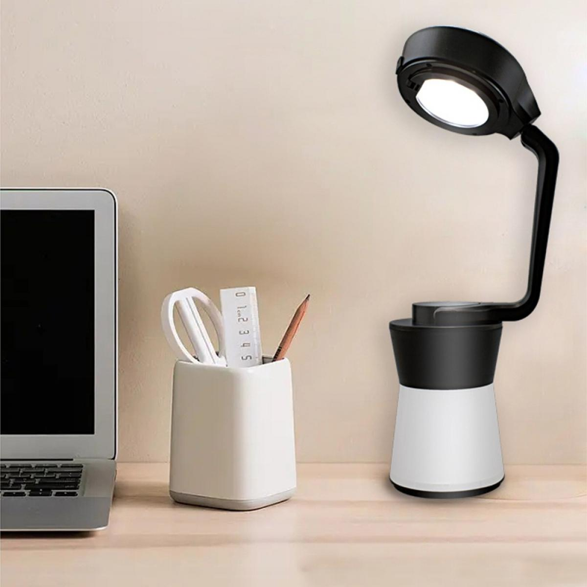 Ein Laptop, ein Stiftebecher mit Schere und Lineal und eine moderne Schreibtischlampe stehen auf einem Schreibtisch.