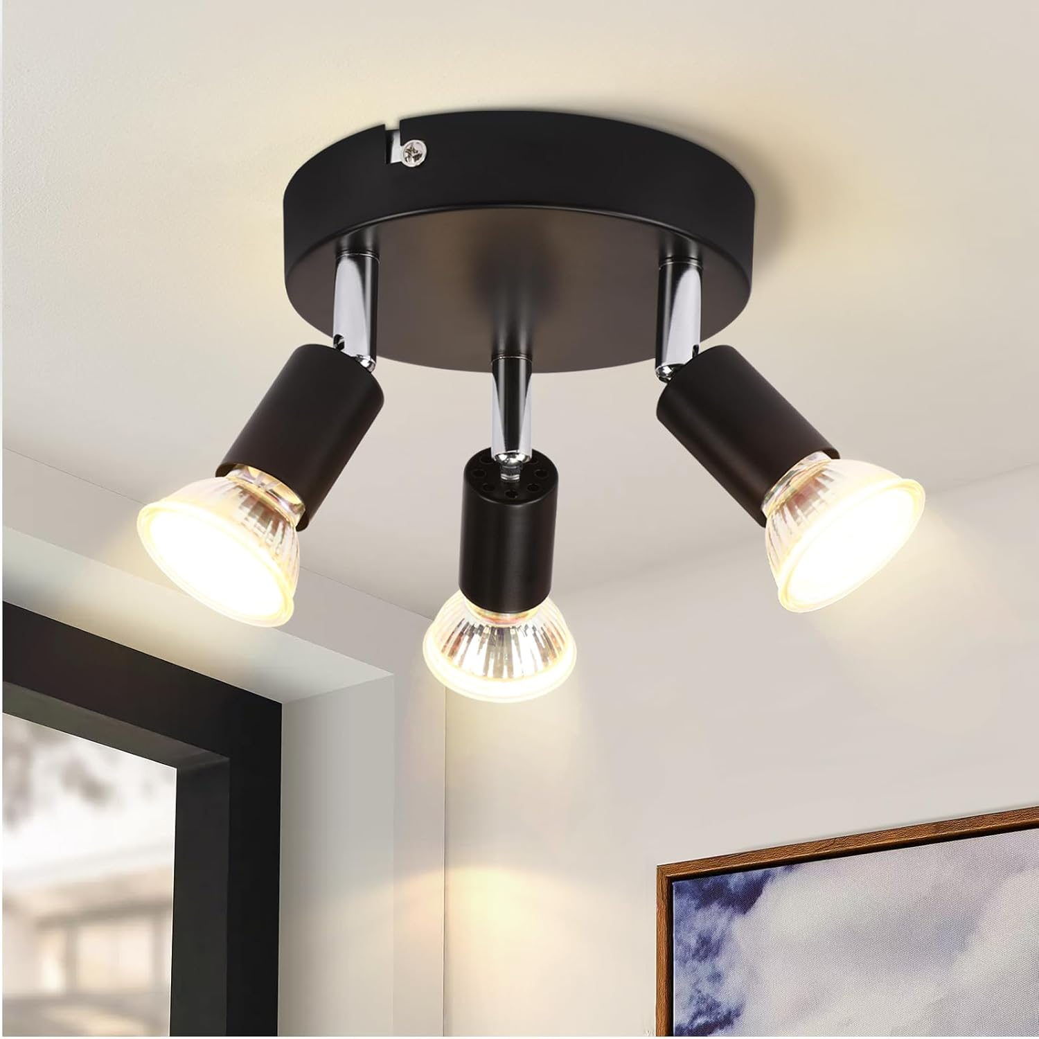 Un lampadario nero con tre faretti regolabili montati su una base rotonda.