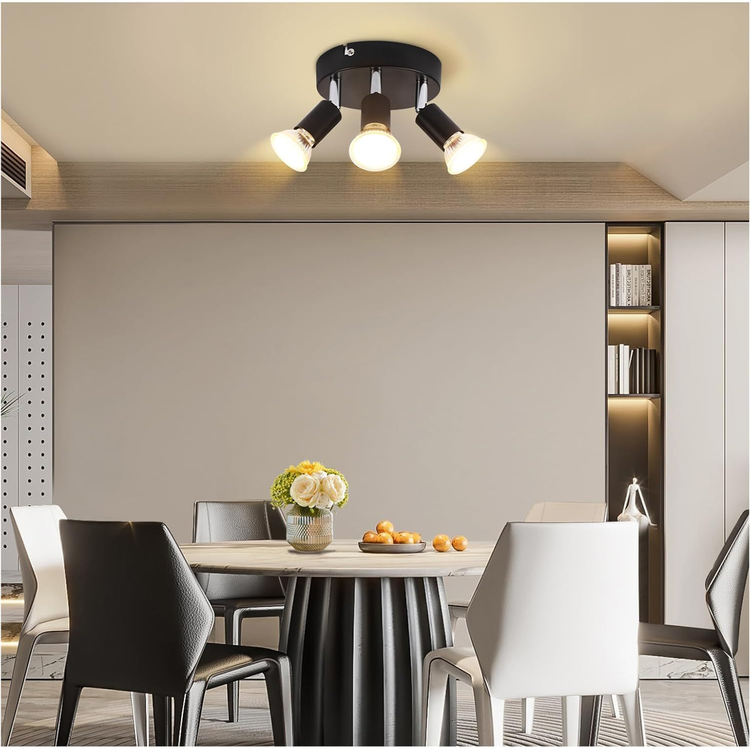 Una sala da pranzo moderna con tavolo rotondo, sedie e plafoniera.