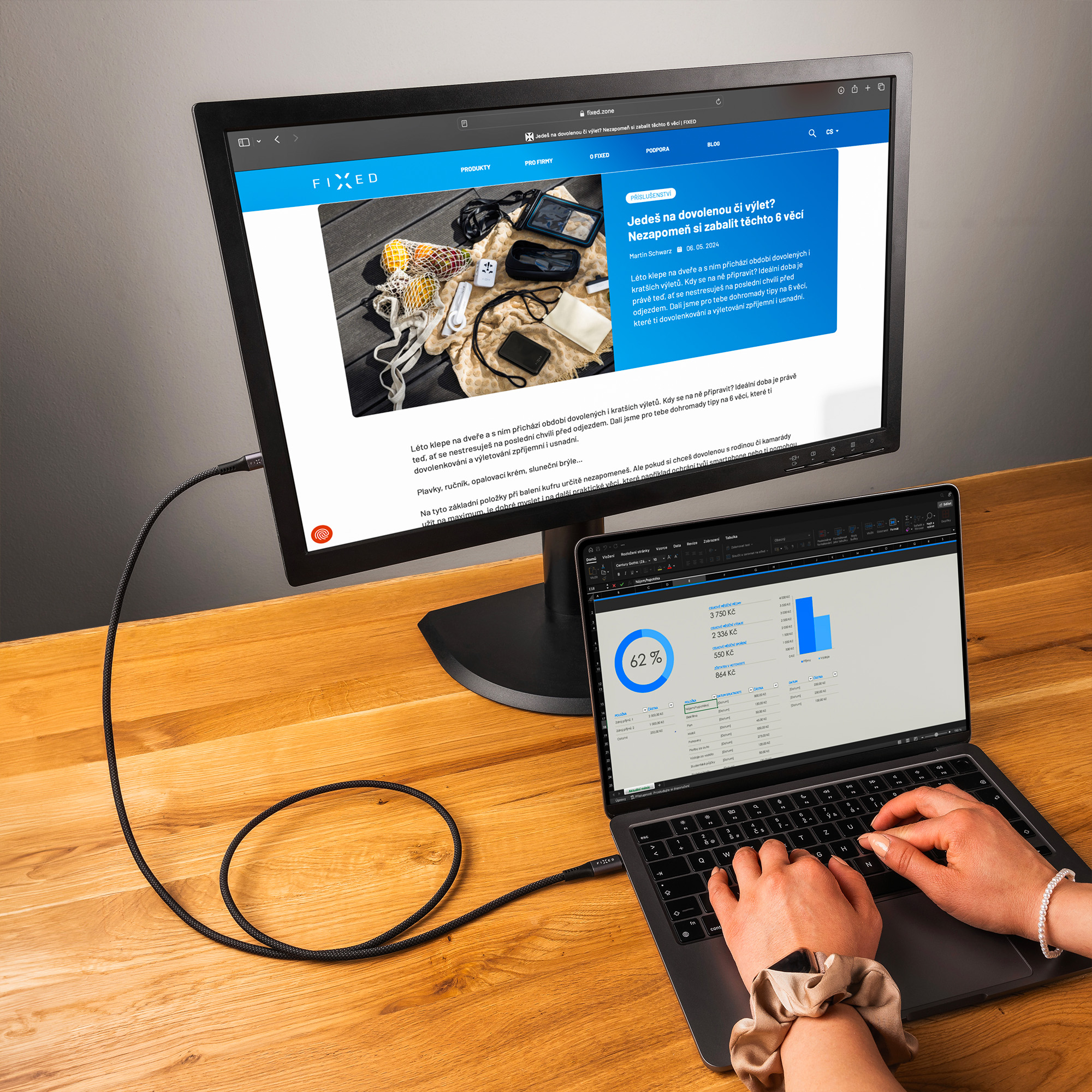 Ein Desktop-Monitor und ein Laptop stehen nebeneinander auf einem Holztisch.