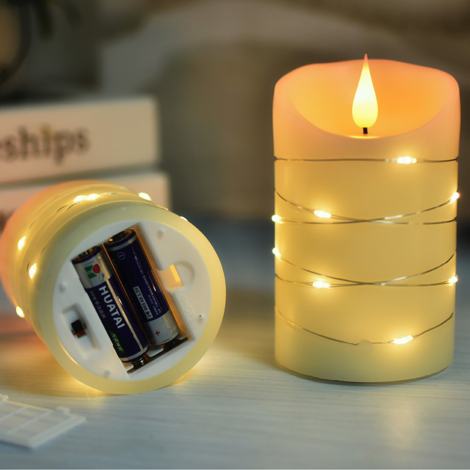 Świeca LED ze światełkami i komorą baterii. Książki w tle.