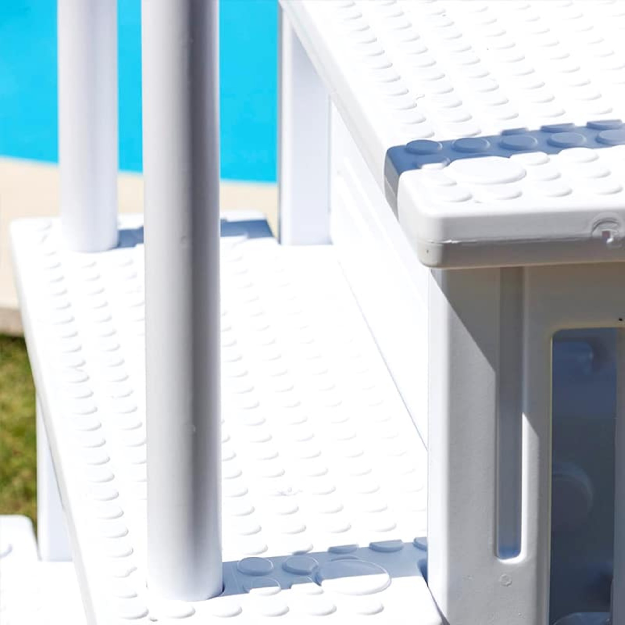 Gradini bianchi per piscina con accenti blu accanto all'acqua blu.