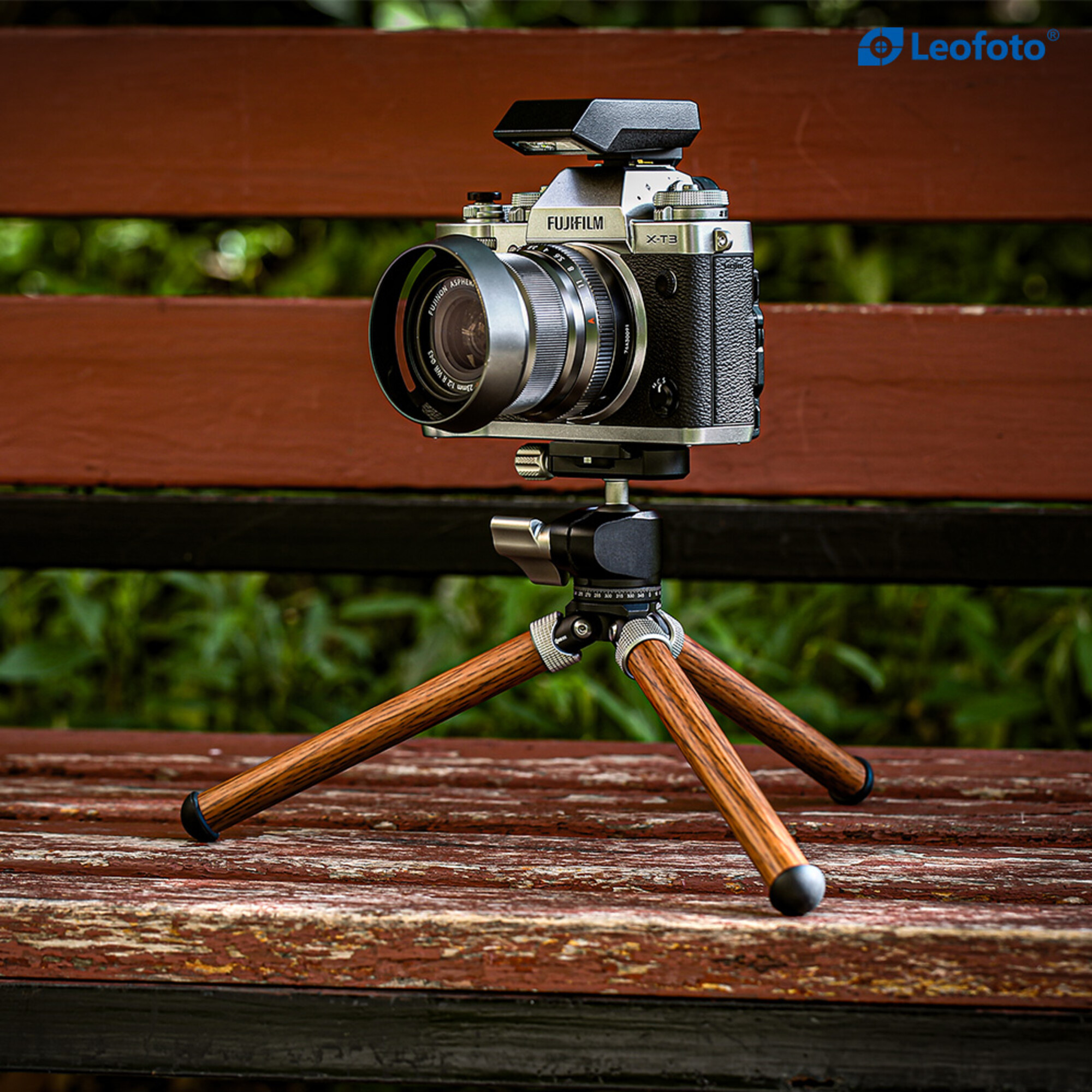 Eine Fujifilm X-T3 Kamera auf einem Holzstativ auf einer Holzbank im Freien.