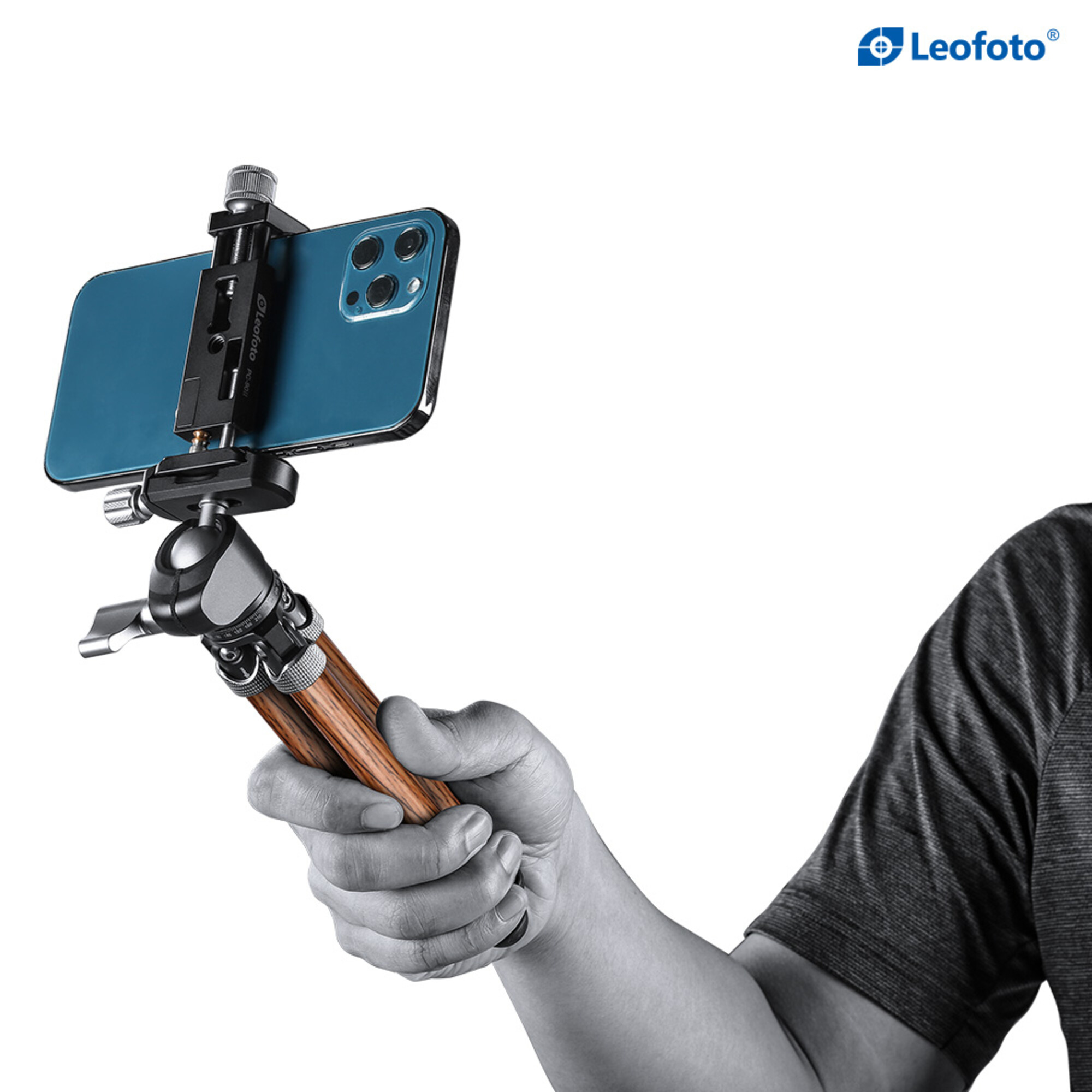 Eine Hand hält ein blaues Smartphone, das an einem kleinen Stativ mit Holzbeinen befestigt ist.