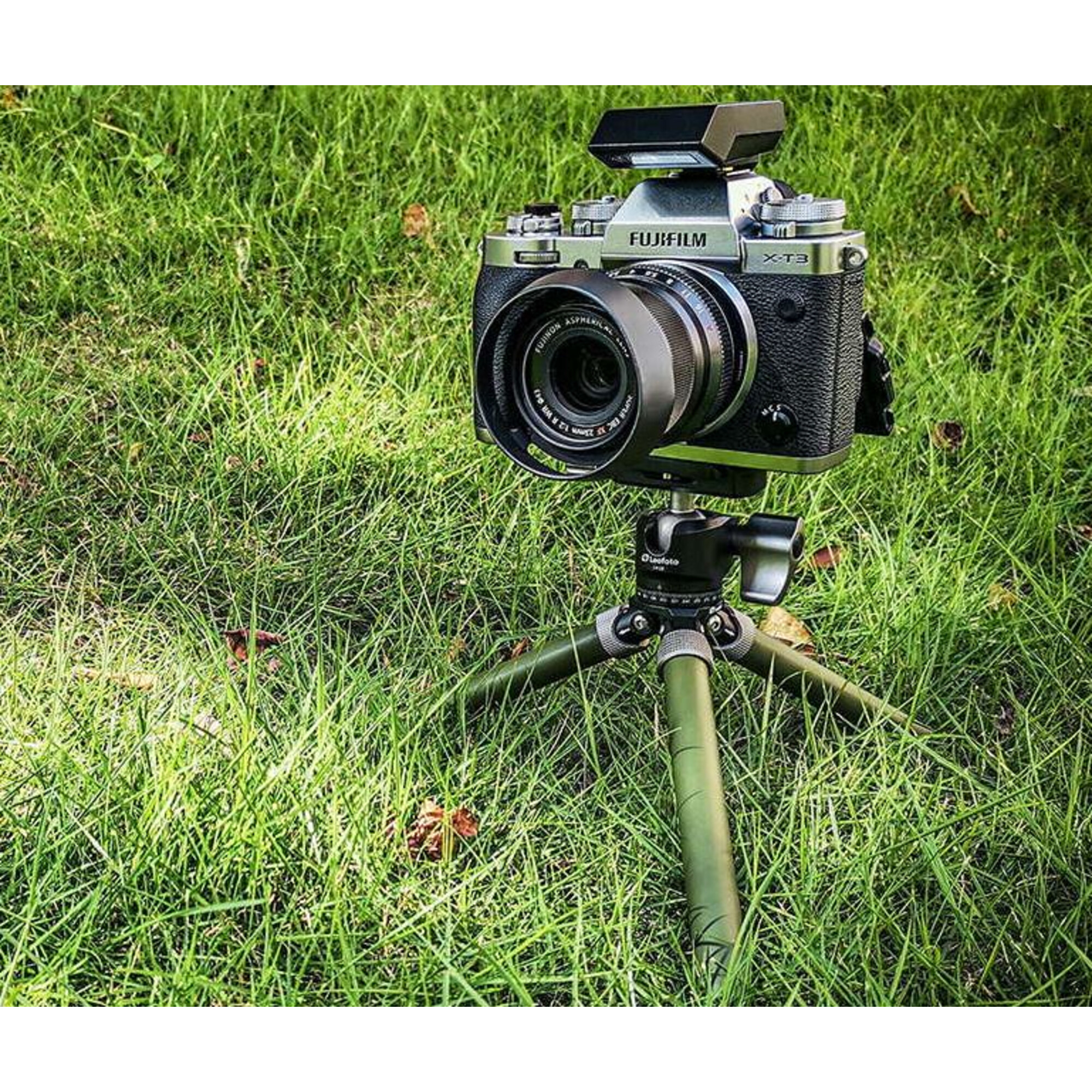 Eine Fujifilm X-T3 Kamera mit Blitz auf einem Stativ im Gras.