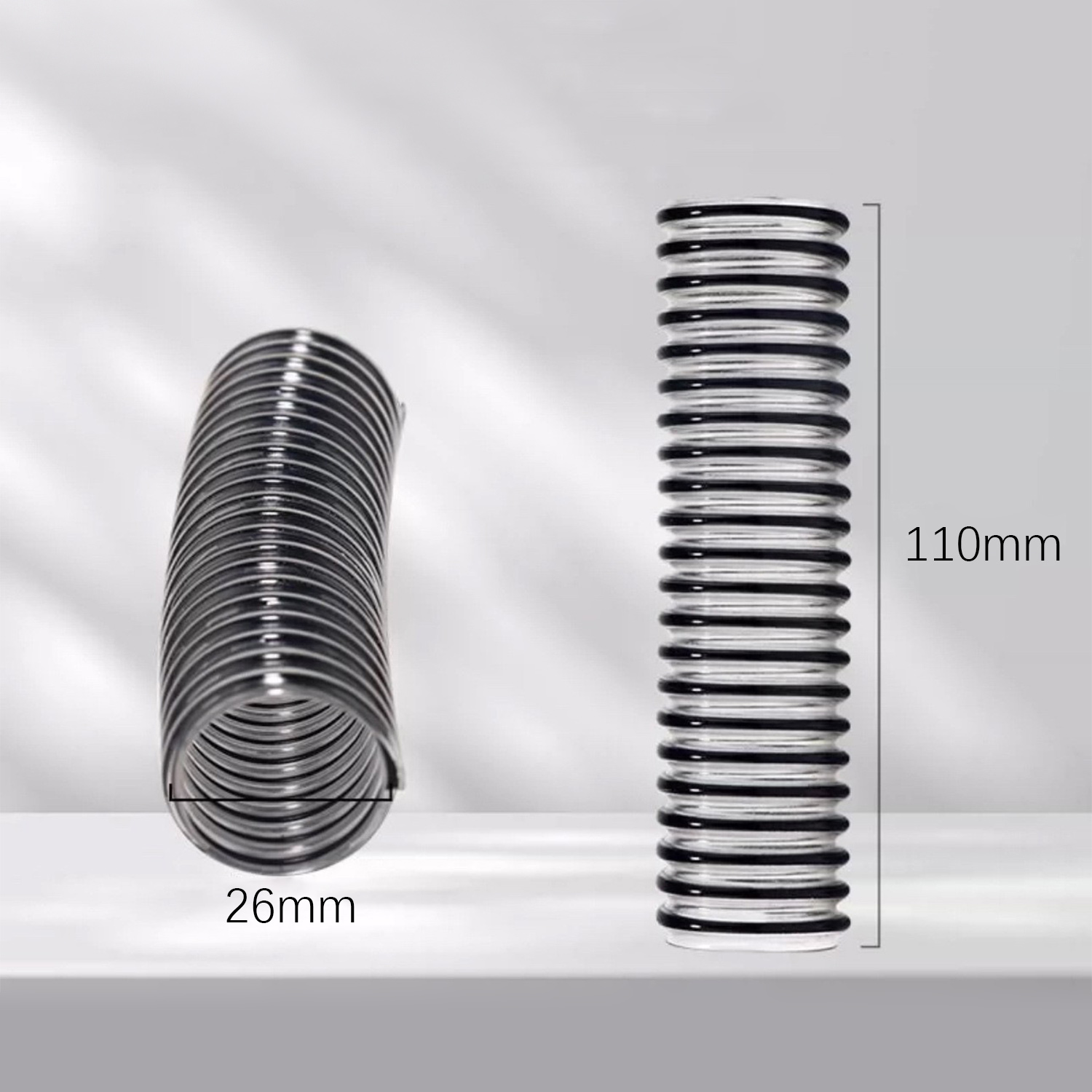 Dwa czarne karbowane węże. Jeden jest zgięty, pokazuje 26mm średnicy. Drugi jest prosty, 110mm długości.