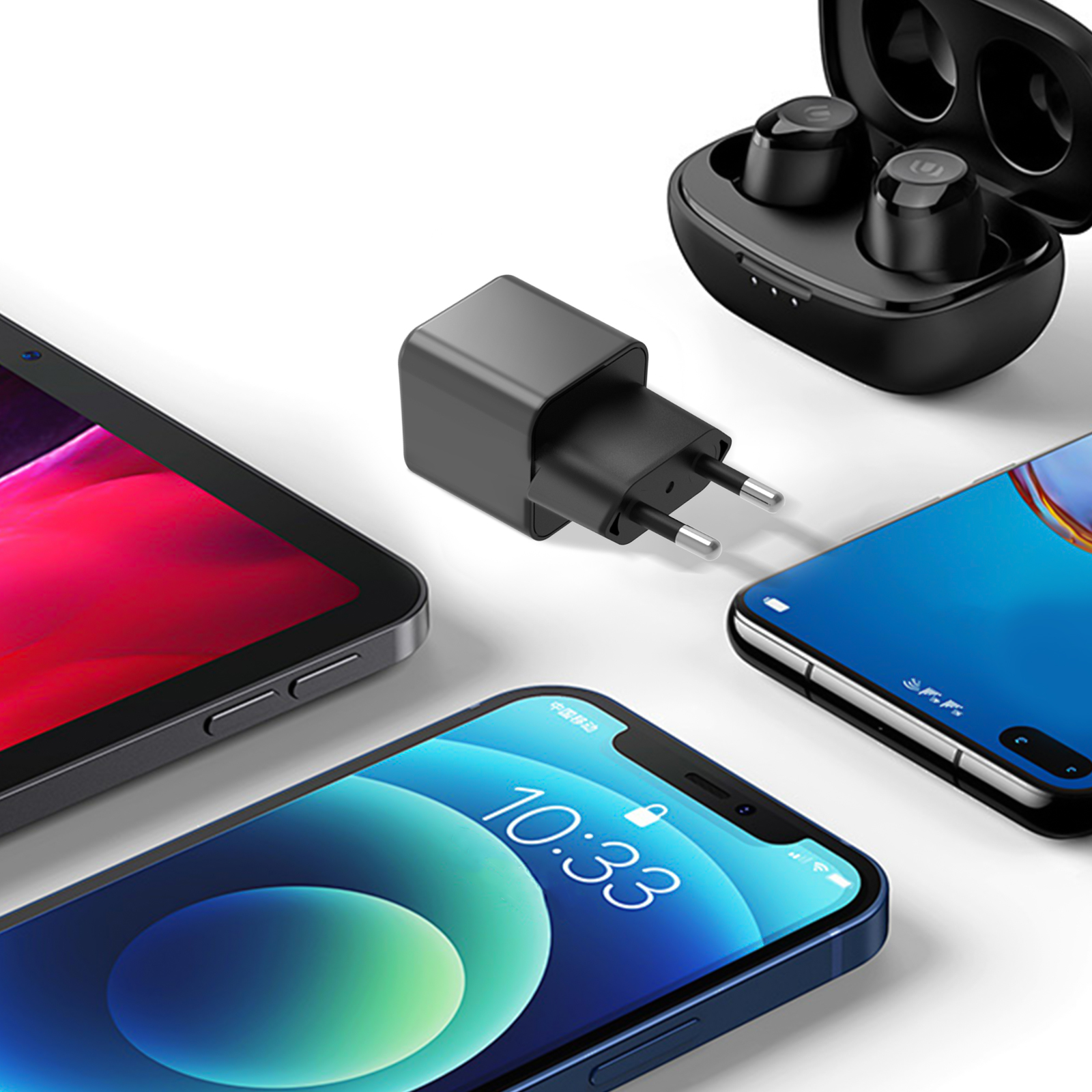 Un caricabatterie nero, un telefono, un tablet e auricolari sono disposti su una superficie bianca.