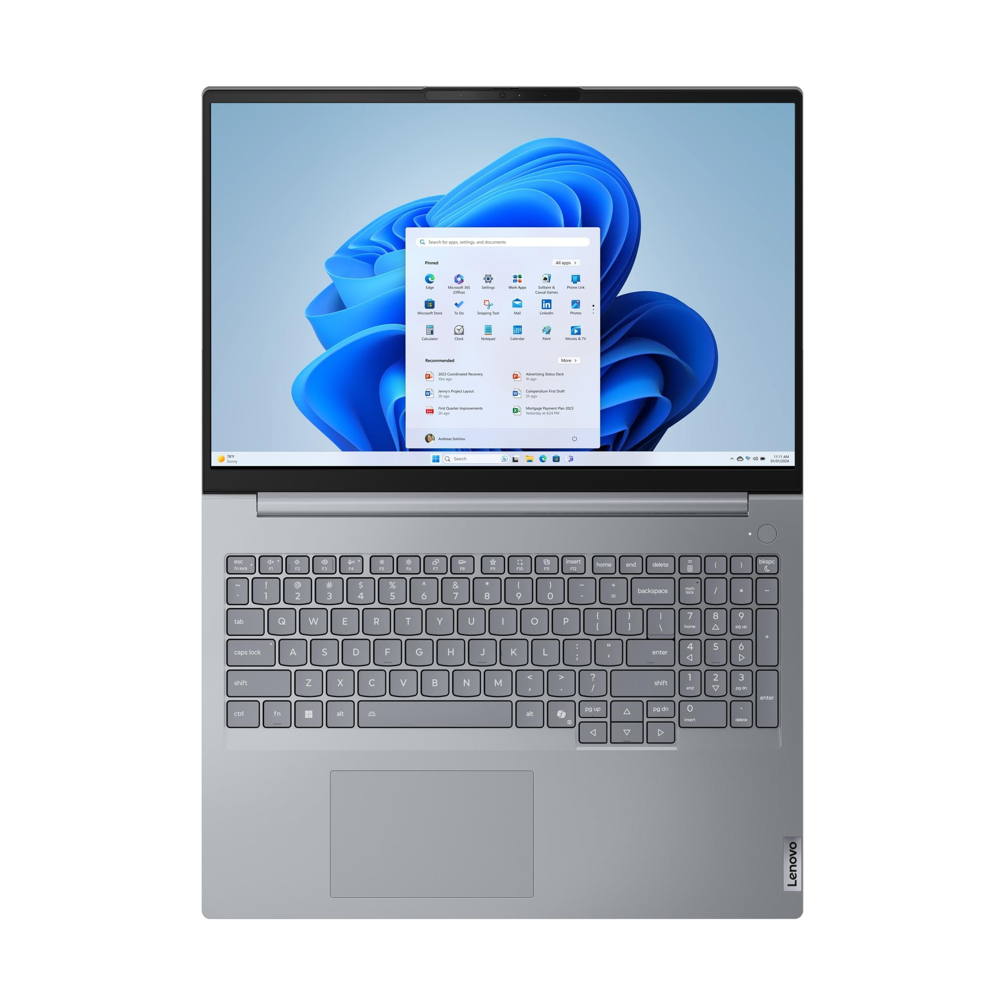 Un laptop Lenovo argentato è aperto, mostrando il menu Start di Windows 11 con sfondo astratto blu.