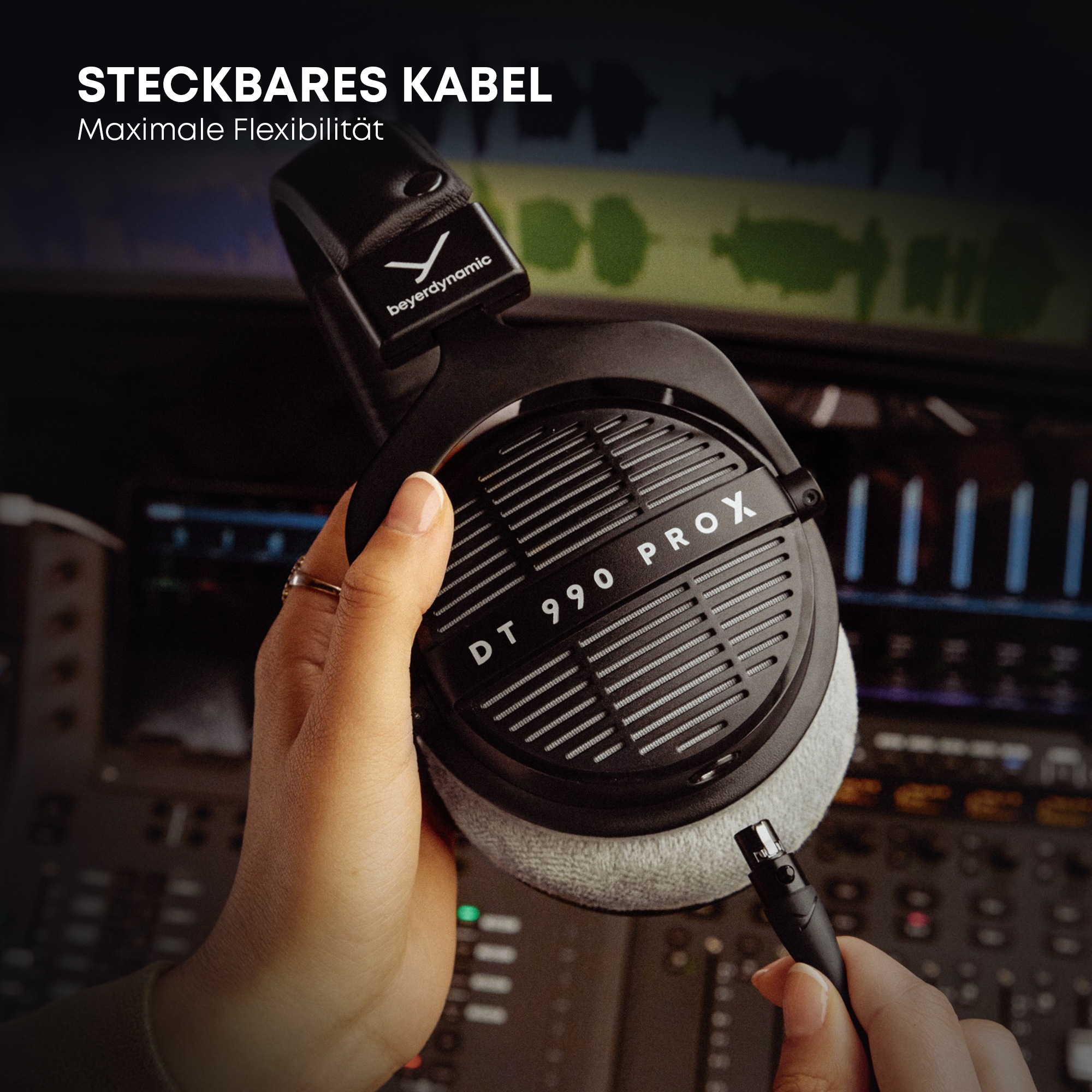 Hand hält Beyerdynamic DT 990 PRO Kopfhörer mit abnehmbarem Kabel, Studio-Hintergrund.