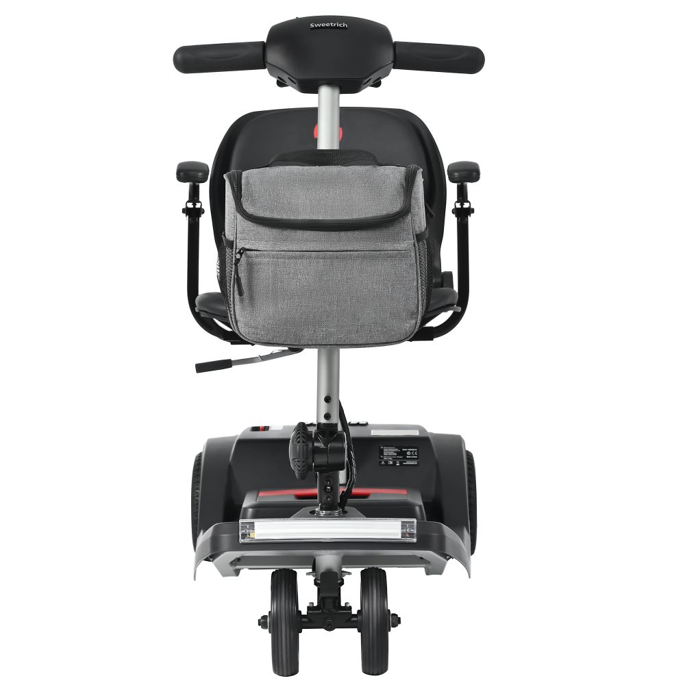 Un scooter de movilidad negro y gris con una bolsa gris unida al poste del asiento.