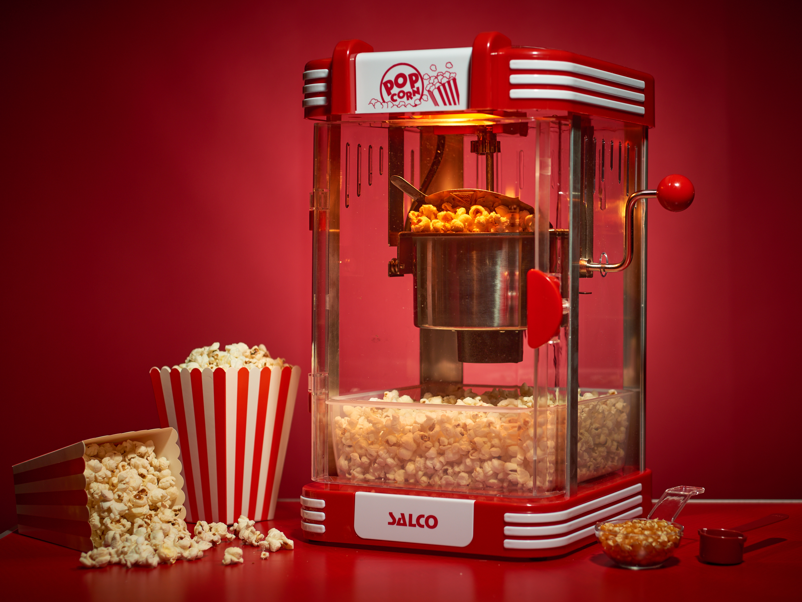 Ein roter Popcornautomat mit Popcorn darin und daneben.