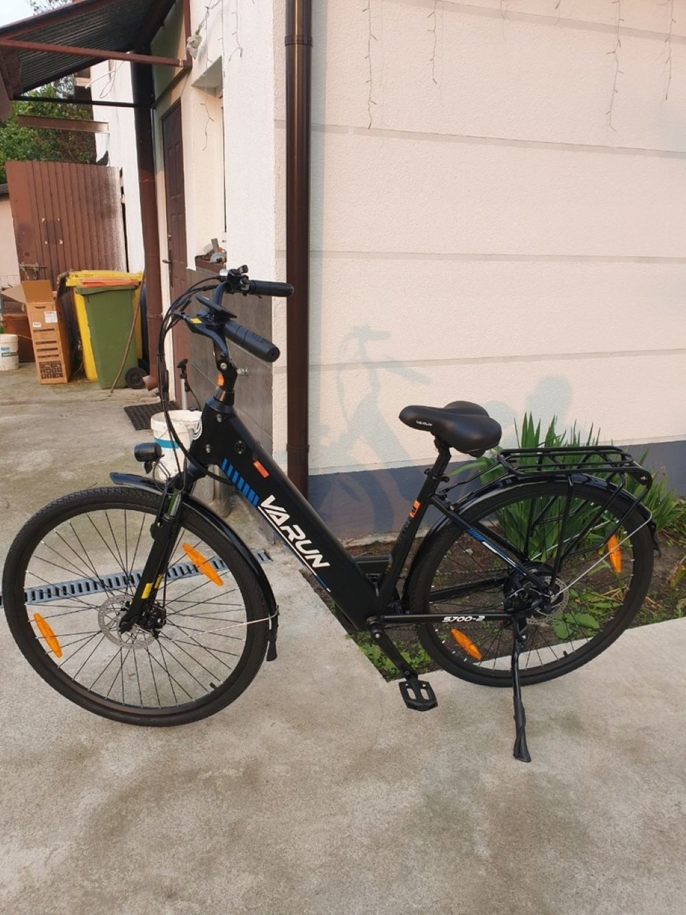 Una bicicleta eléctrica VARUN negra está sobre un camino de concreto.