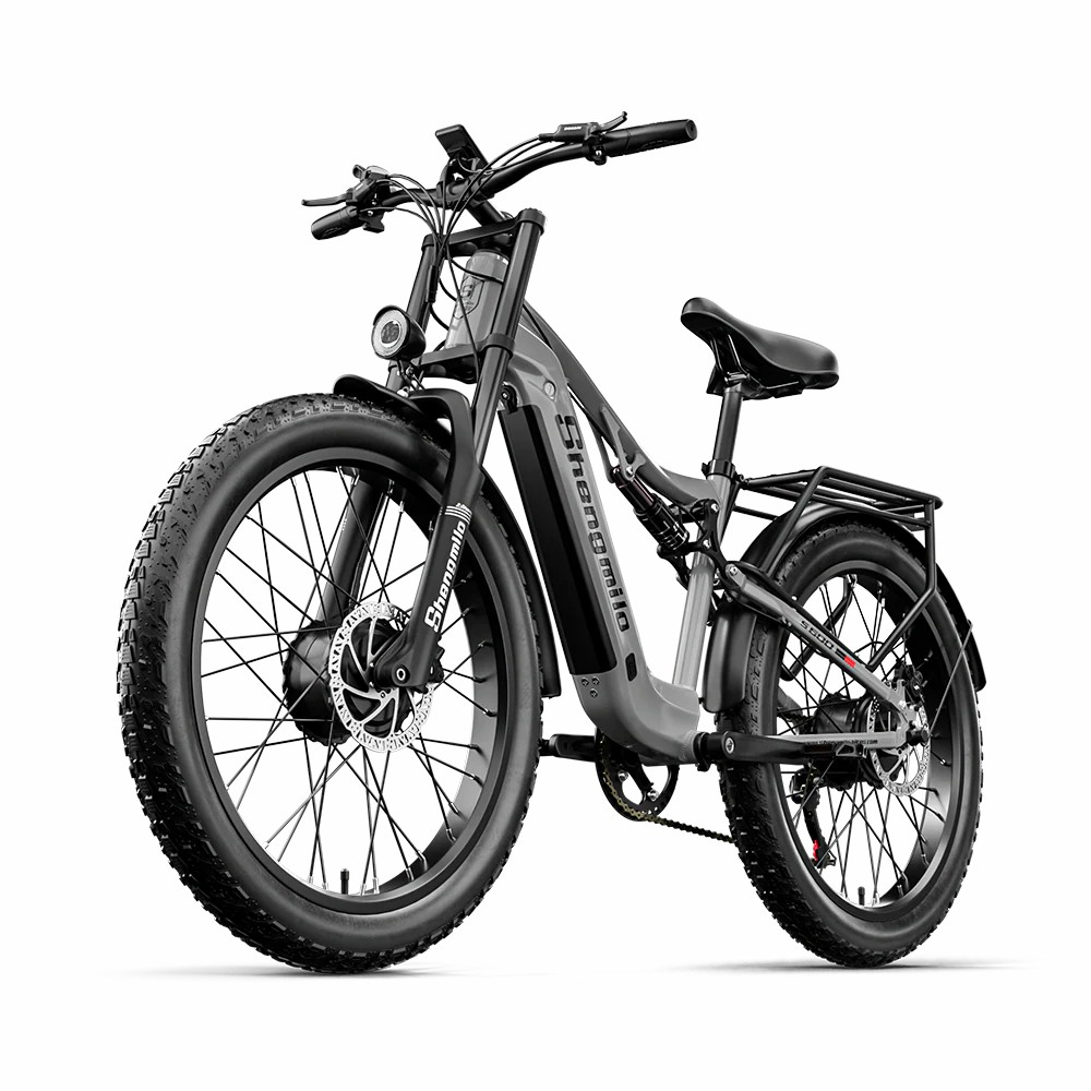 Una bicicleta de montaña eléctrica gris con neumáticos anchos y portaequipajes trasero.