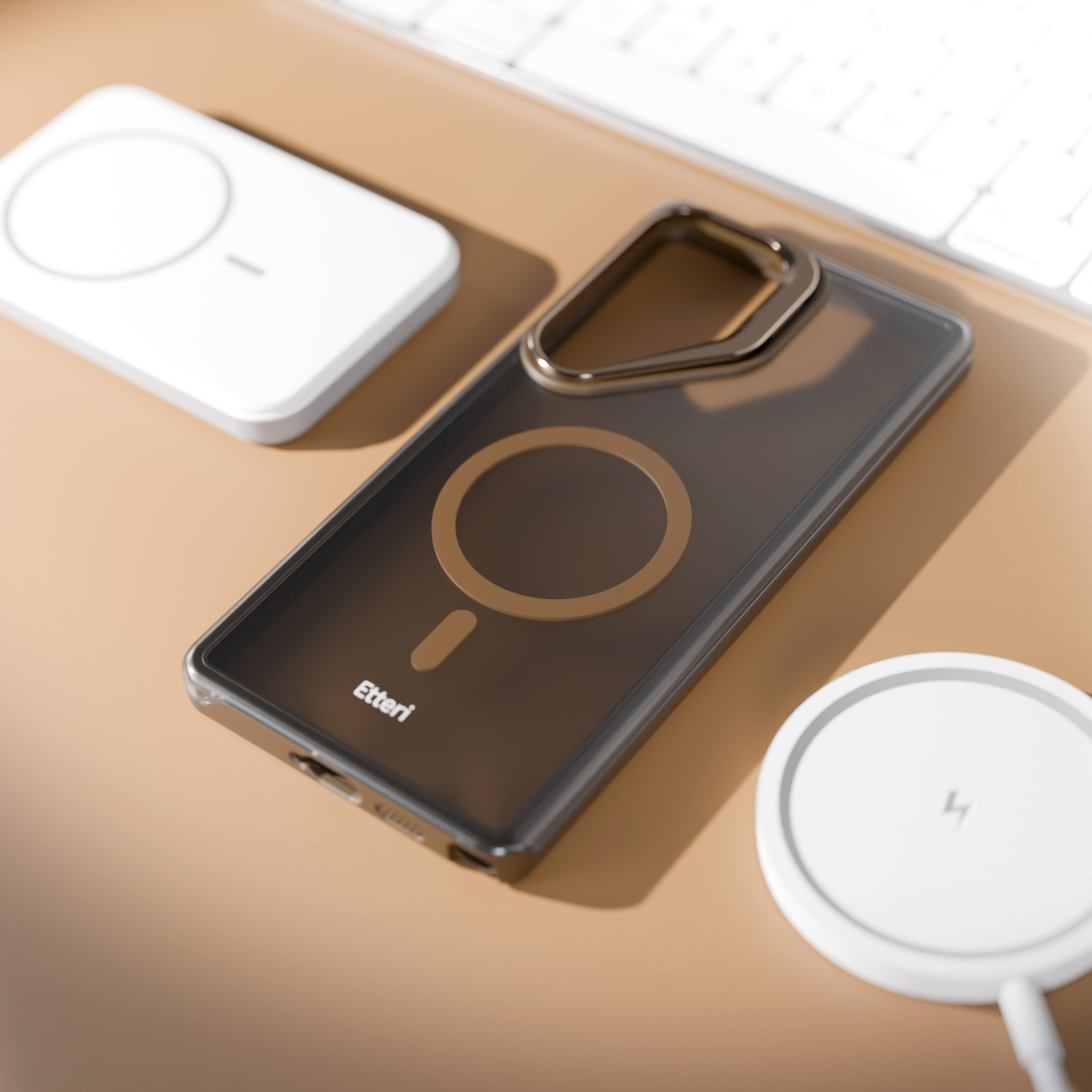 Cover per telefono traslucida scura con anello magnetico su superficie marrone vicino a due caricabatterie wireless e tastiera.