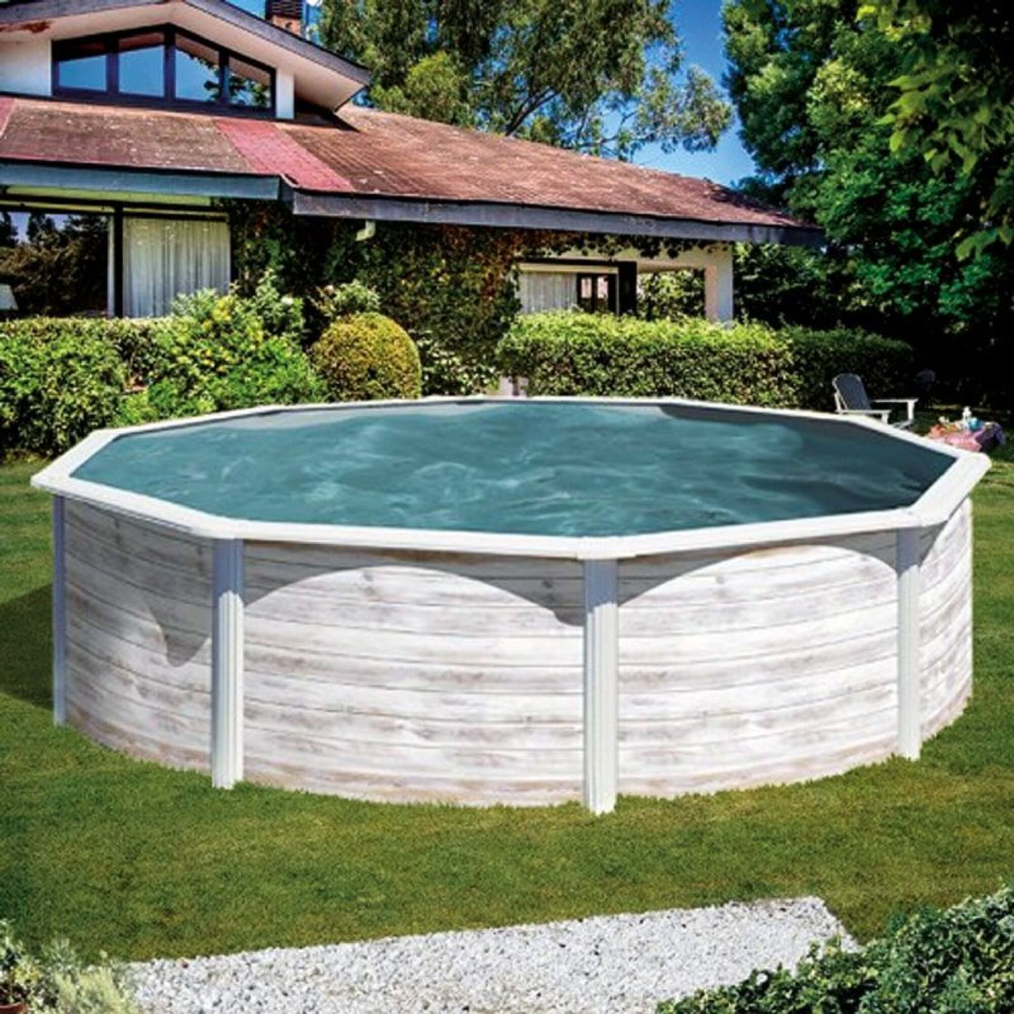 Una piscina grande y redonda de aspecto de madera se encuentra sobre césped verde, con una casa al fondo.