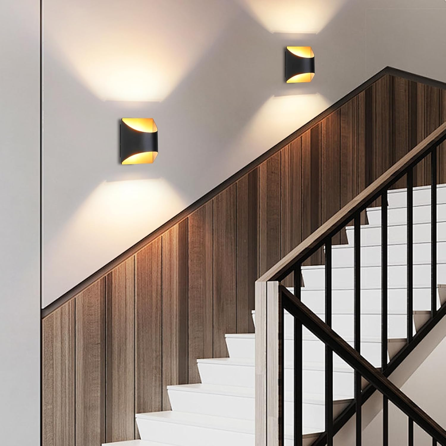 Scala moderna con pannellatura in legno e ringhiera nera, illuminata da due applique.