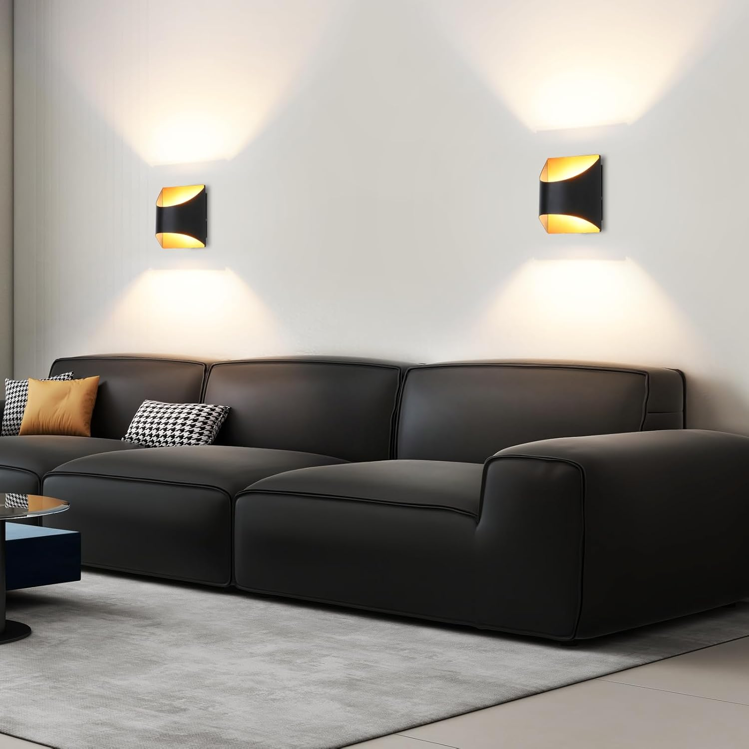 Un moderno divano nero con cuscini decorativi è posto su un tappeto grigio davanti a due applique.