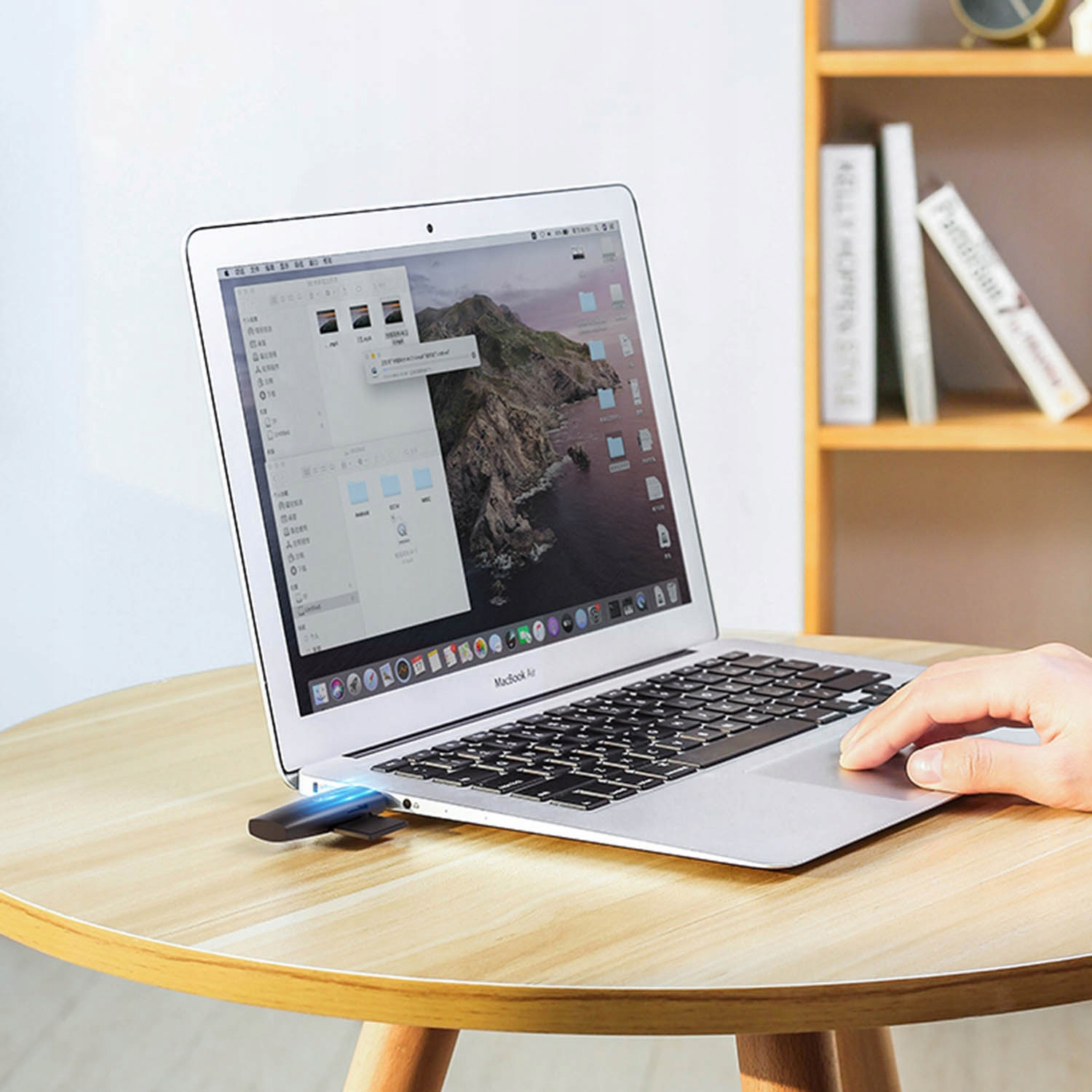 Pendrive jest podłączony do MacBooka Air na drewnianym stole.