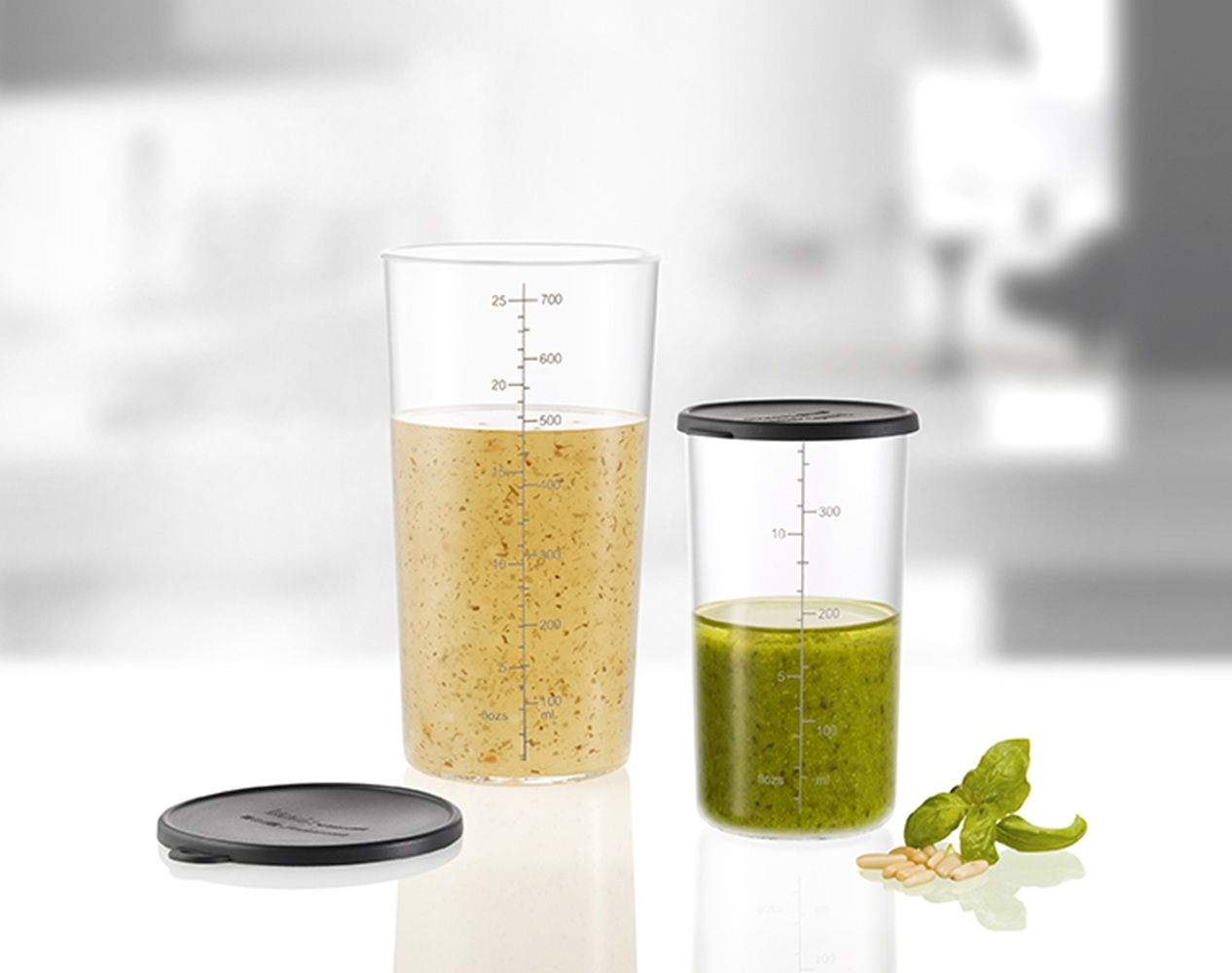 Zwei Messbecher mit Flüssigkeiten, einer mit gelber Flüssigkeit, der andere mit grüner.