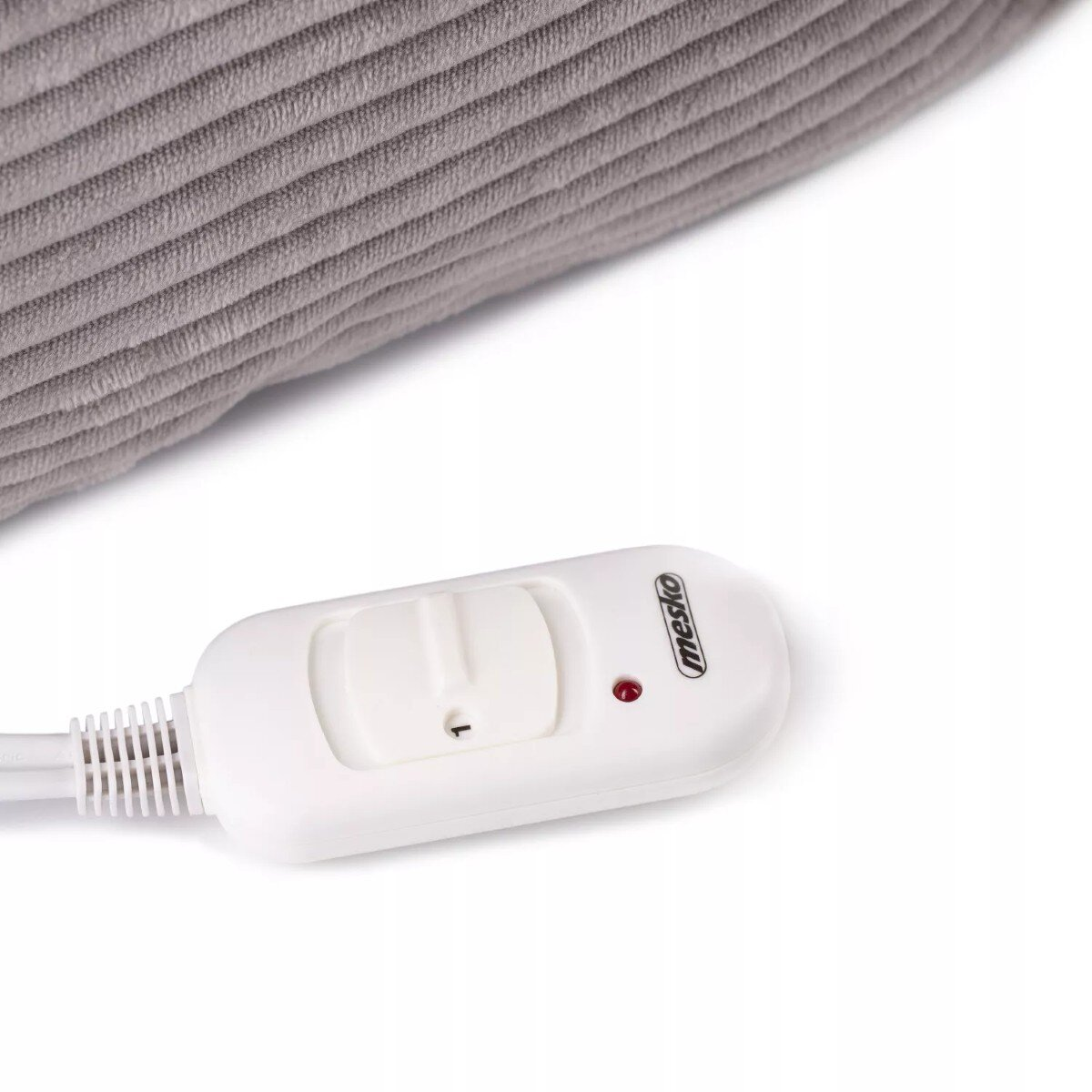 Zbliżenie na szary materiał sztruksowy z białym kontrolerem koca elektrycznego.