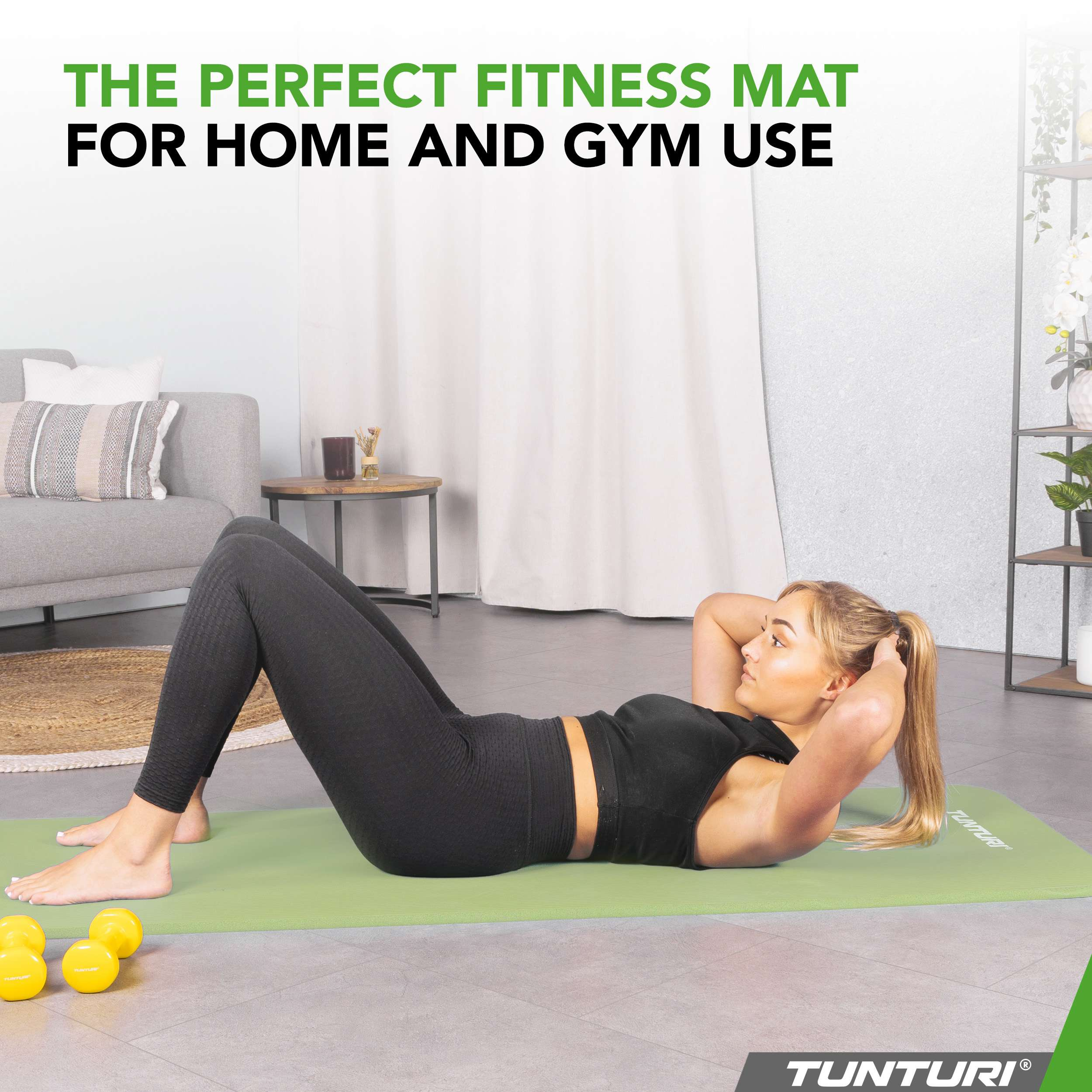 A woman does crunches on a green mat with dumbbells nearby.