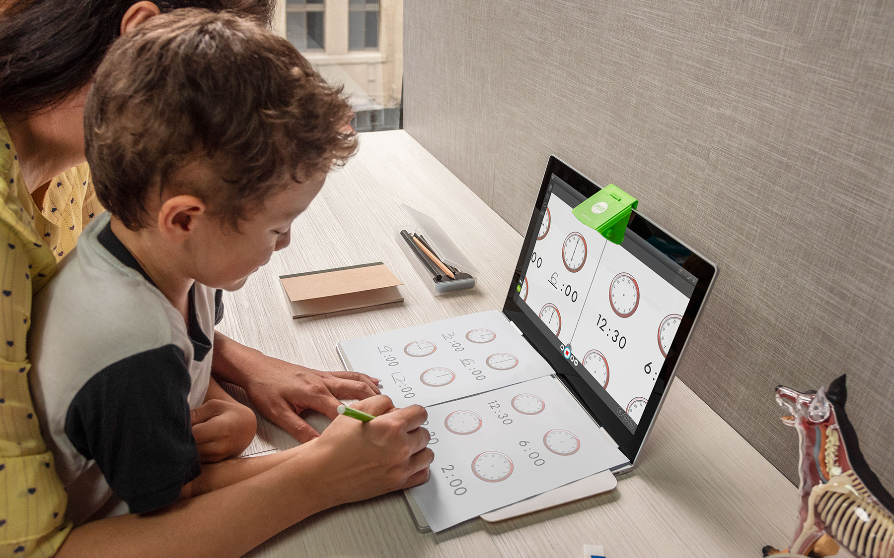 Un bambino e un adulto imparano l'ora con un laptop e fogli di lavoro.