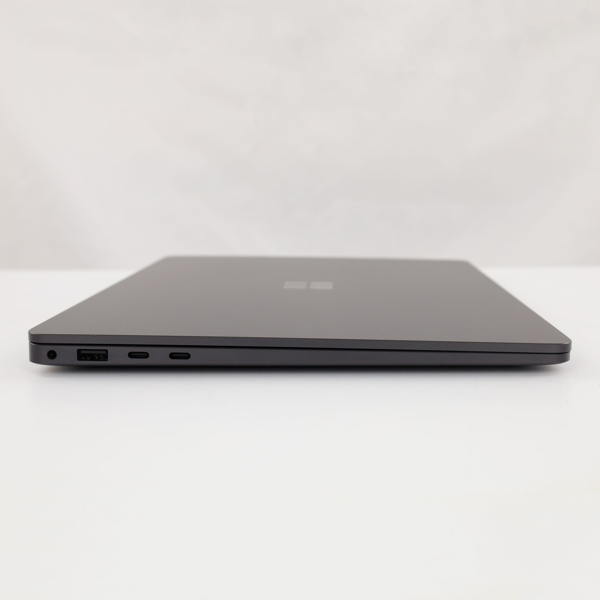 Seitenansicht eines geschlossenen dunkelgrauen Laptops mit Anschlüssen: USB-A, USB-C und Kopfhörerbuchse.