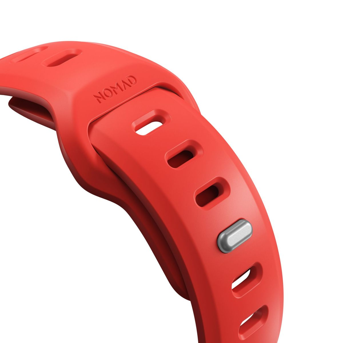 Primo piano di un cinturino per orologio in silicone rosso con logo 'NOMAD' in rilievo.