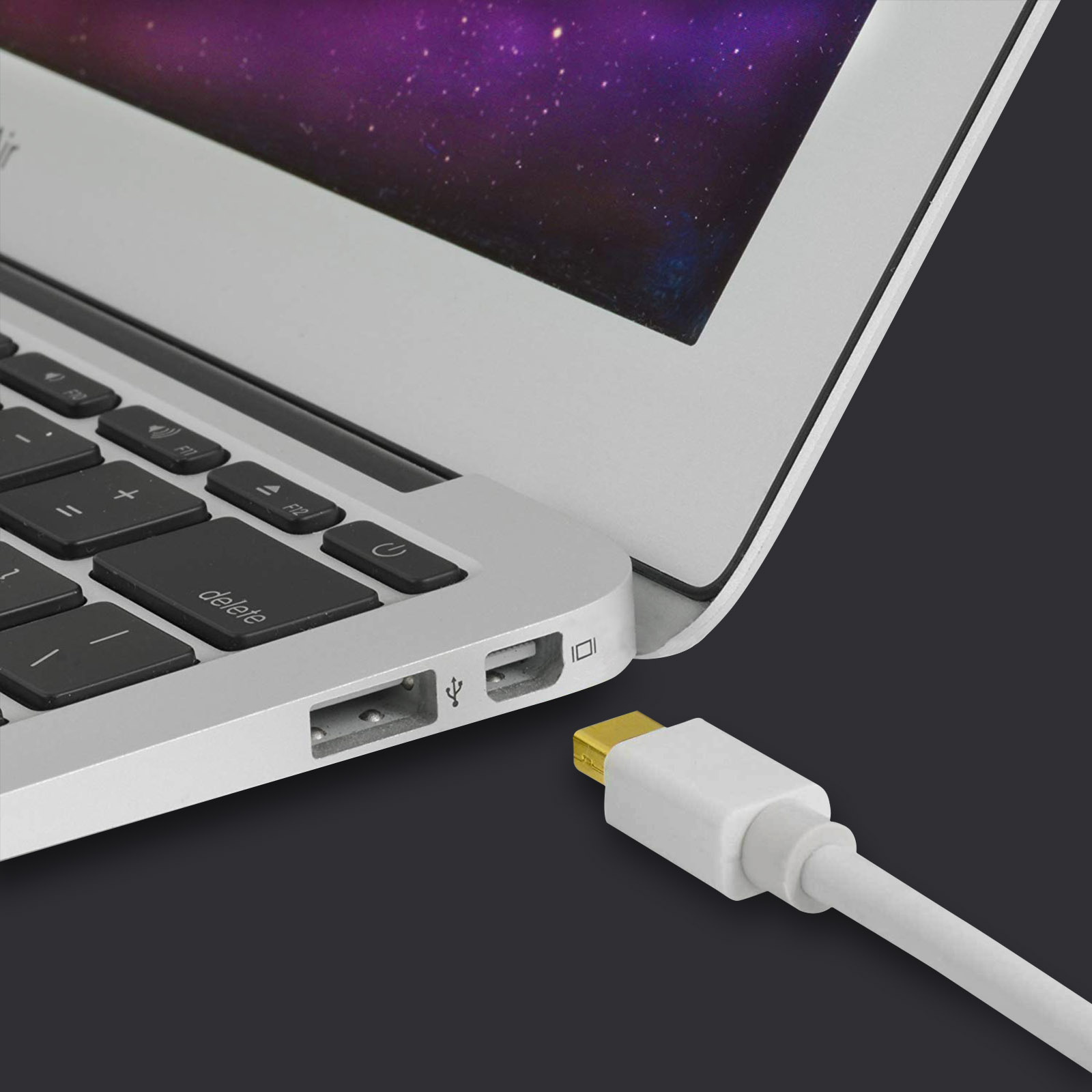 Un cavo bianco con connettore dorato viene inserito nella porta USB di un laptop argento.